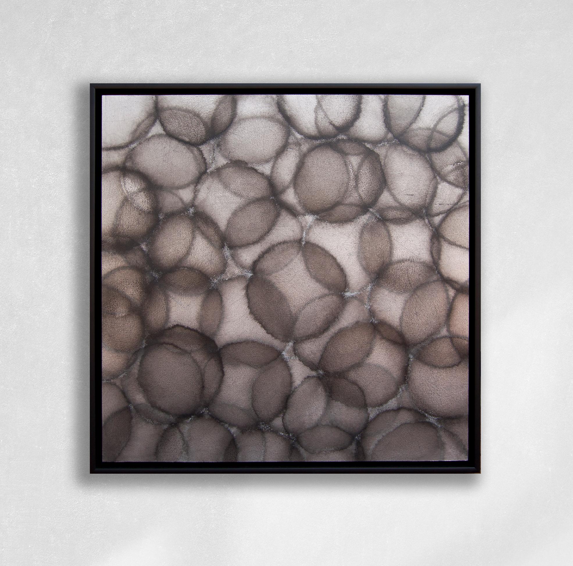 This abstract painting is made with acrylic paint over metal leaf on cradled panel. It features a charcoal grey palette, with translucent circular shapes layered over one another creating darker shapes where the circles overlap. The painting itself