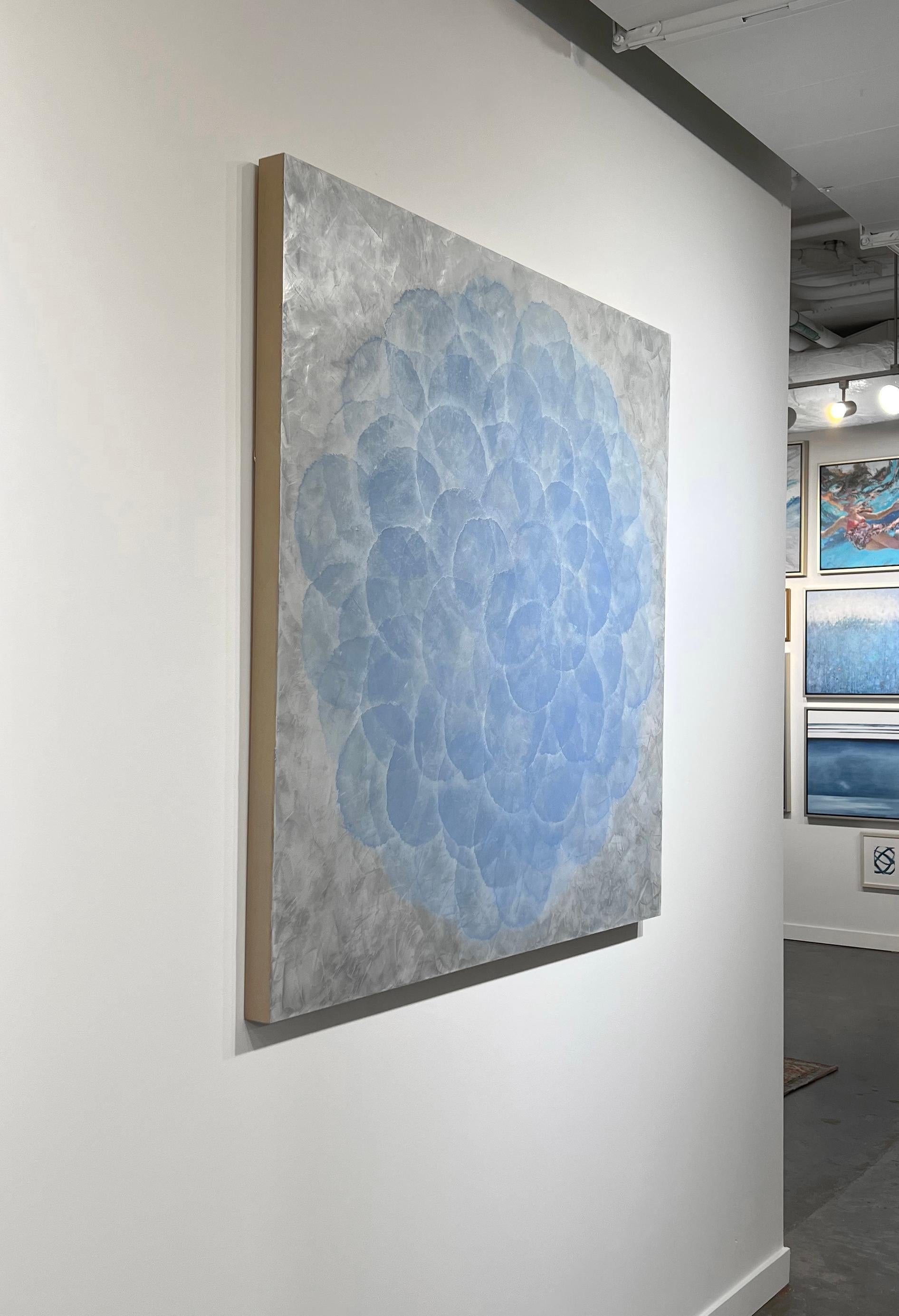 This abstract painting by Roger Mudre is made with acrylic paint over metal leaf on panel. It features nearly opaque light blue circles, arranged in an overlapping pattern to create a larger circle shape. The outer layer of the circle blends into