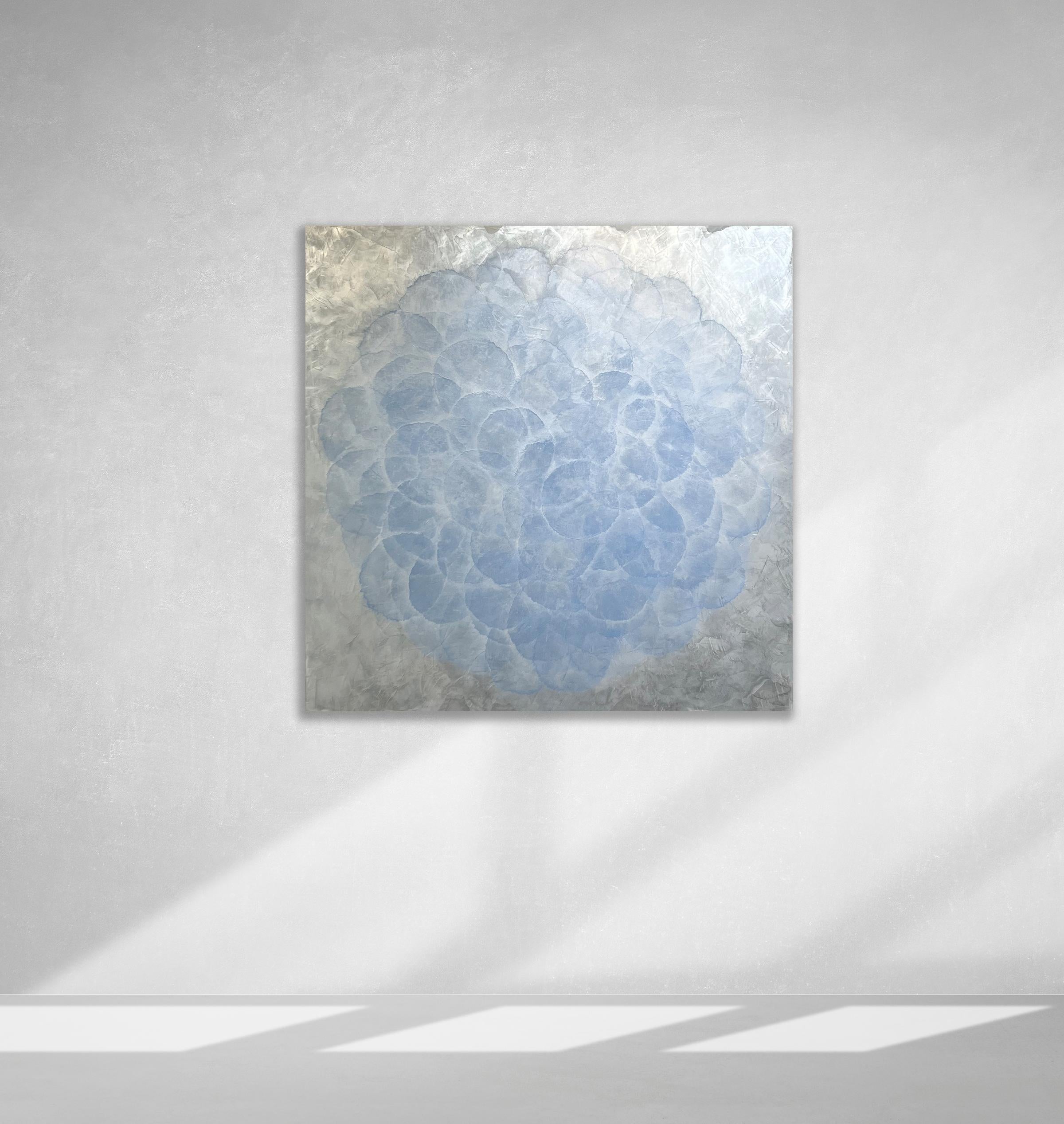 This abstract painting by Roger Mudre is made with acrylic paint over metal leaf on panel. It features nearly opaque light blue circles, arranged in an overlapping pattern to create a larger circle shape. The outer layer of the circle blends into