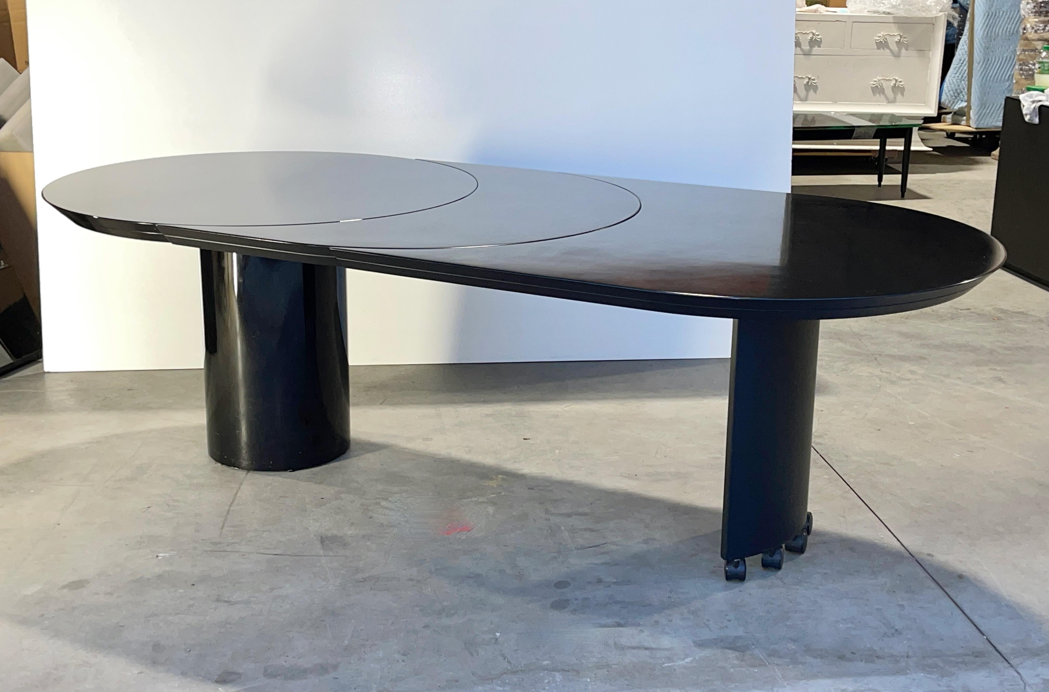 Model 3600-50 extension dining table by Roger Rougier consisting of a 44 inch diameter round pedestal dining table in gloss polished black lacquer with a 33 inch elongated crescent moon extension operated by a clever extending mechanism,