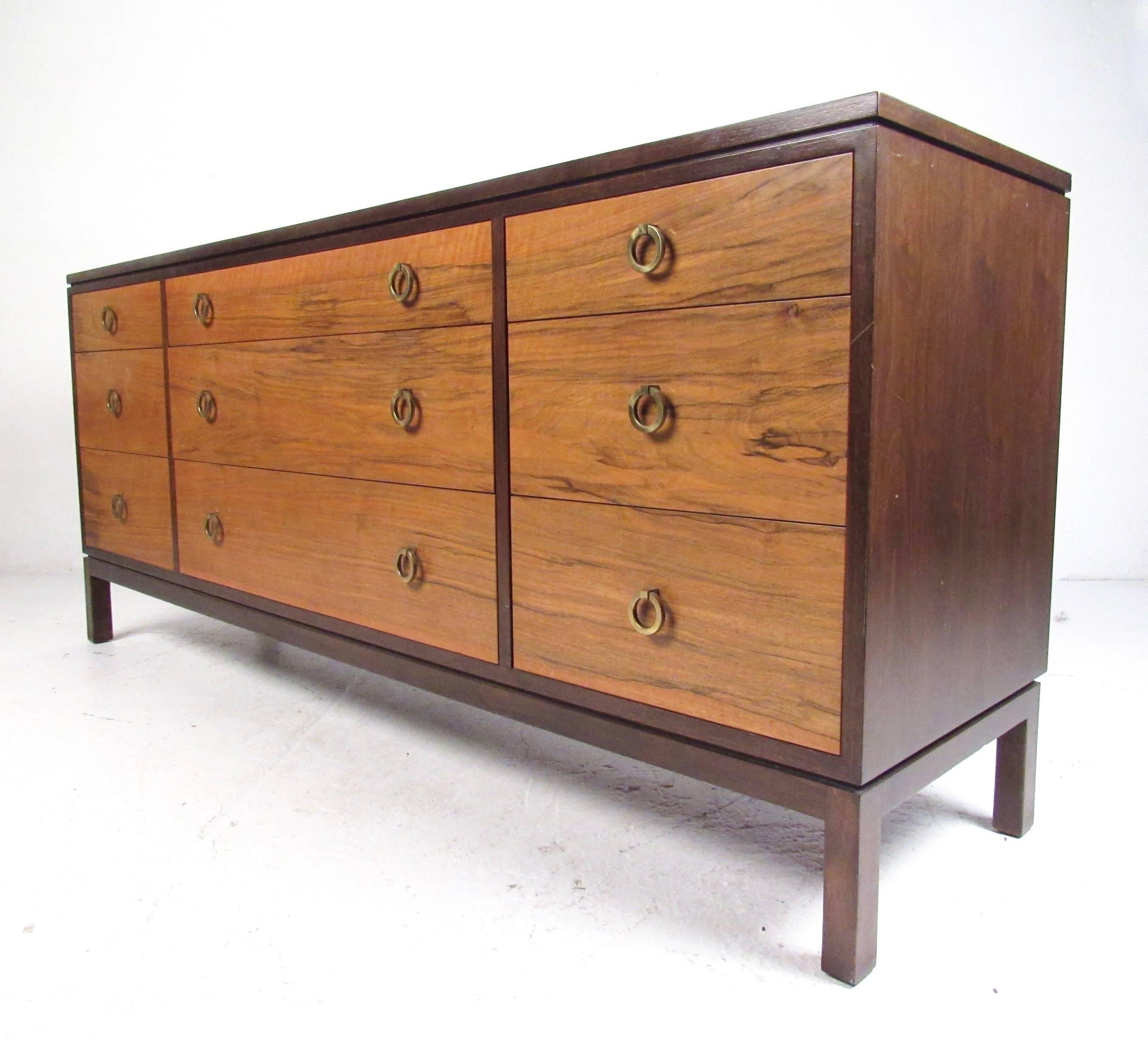This stunning nine drawer bedroom dresser features unique vintage wood finish with iconic brass ring drawer pulls. This spacious low dresser was designed by Roger Sprunger (model #6423) for Dunbar furniture and makes an impressive addition to any
