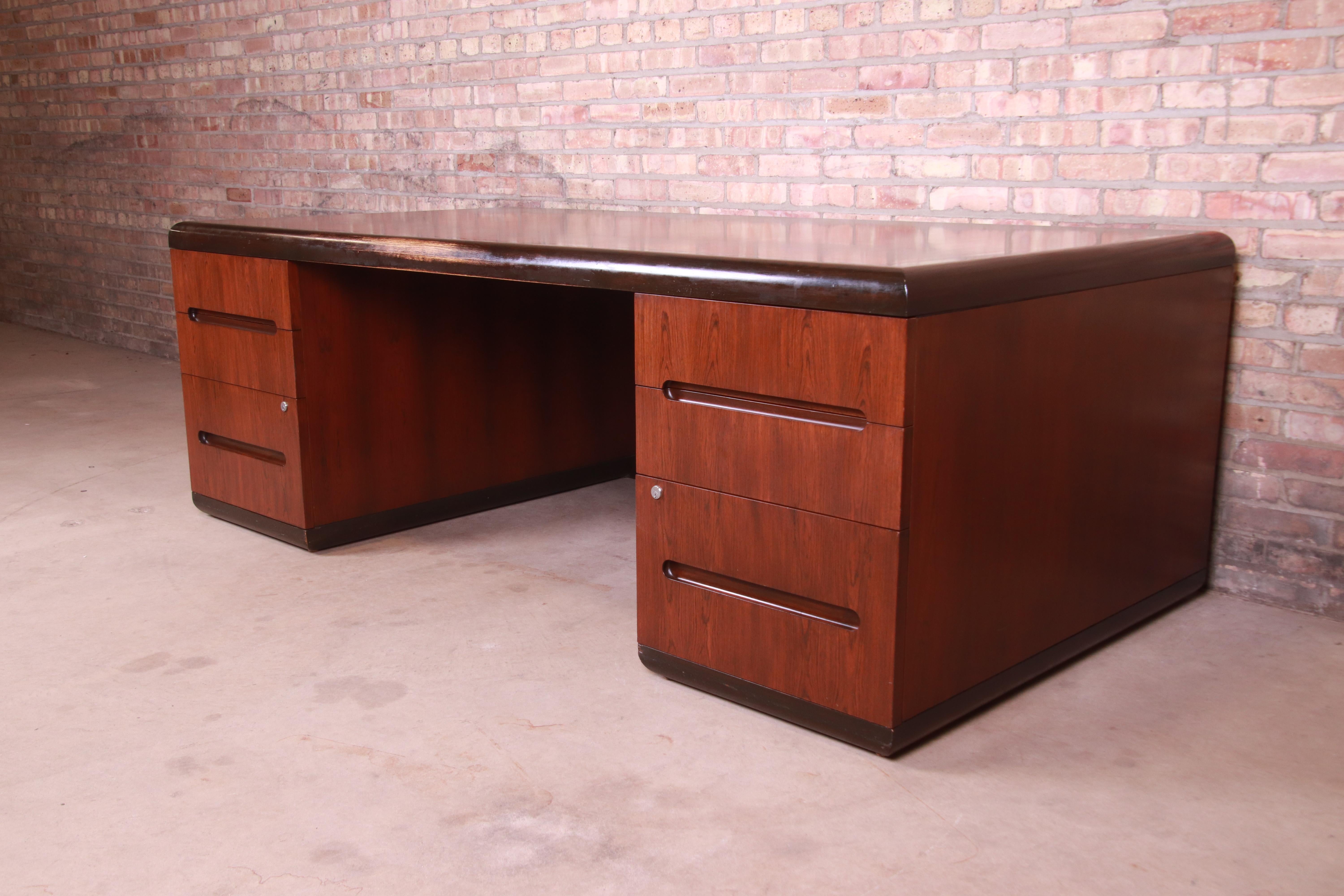 An outstanding Mid-Century Modern six-drawer executive desk

By Roger Sprunger for Dunbar Furniture

USA, 1970s

Book-matched rosewood, with stained oak trim. Custom glass top included.

Measures: 84