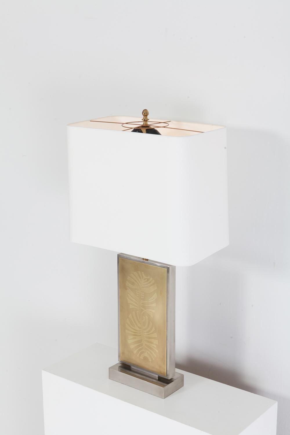 Hollywood Regency 1970s huge and impressive table lamp signed by the artist, Roger Vanhevel.
Stainless steel chromed frame; brass etched artwork in the centre and a new white linen shade on top.
Would fit well in an eclectic maximalist