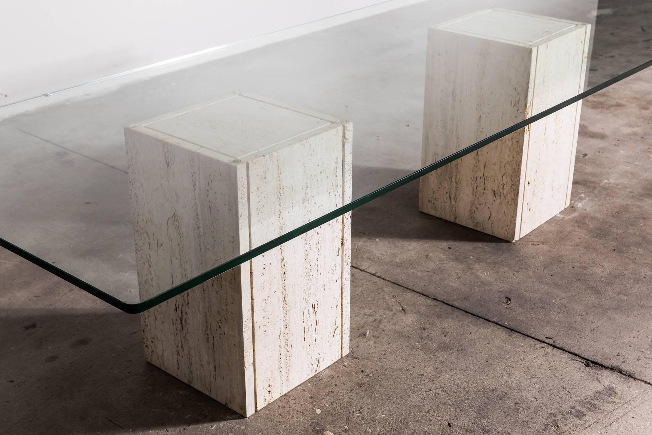 Le magnifique plateau en verre (2 cm) a des bords arrondis et repose sur deux blocs de travertin massif. Peut être utilisée comme table de salle à manger ou de conférence. Produit par Roger Vanhevel, 1970, Belgique.

 