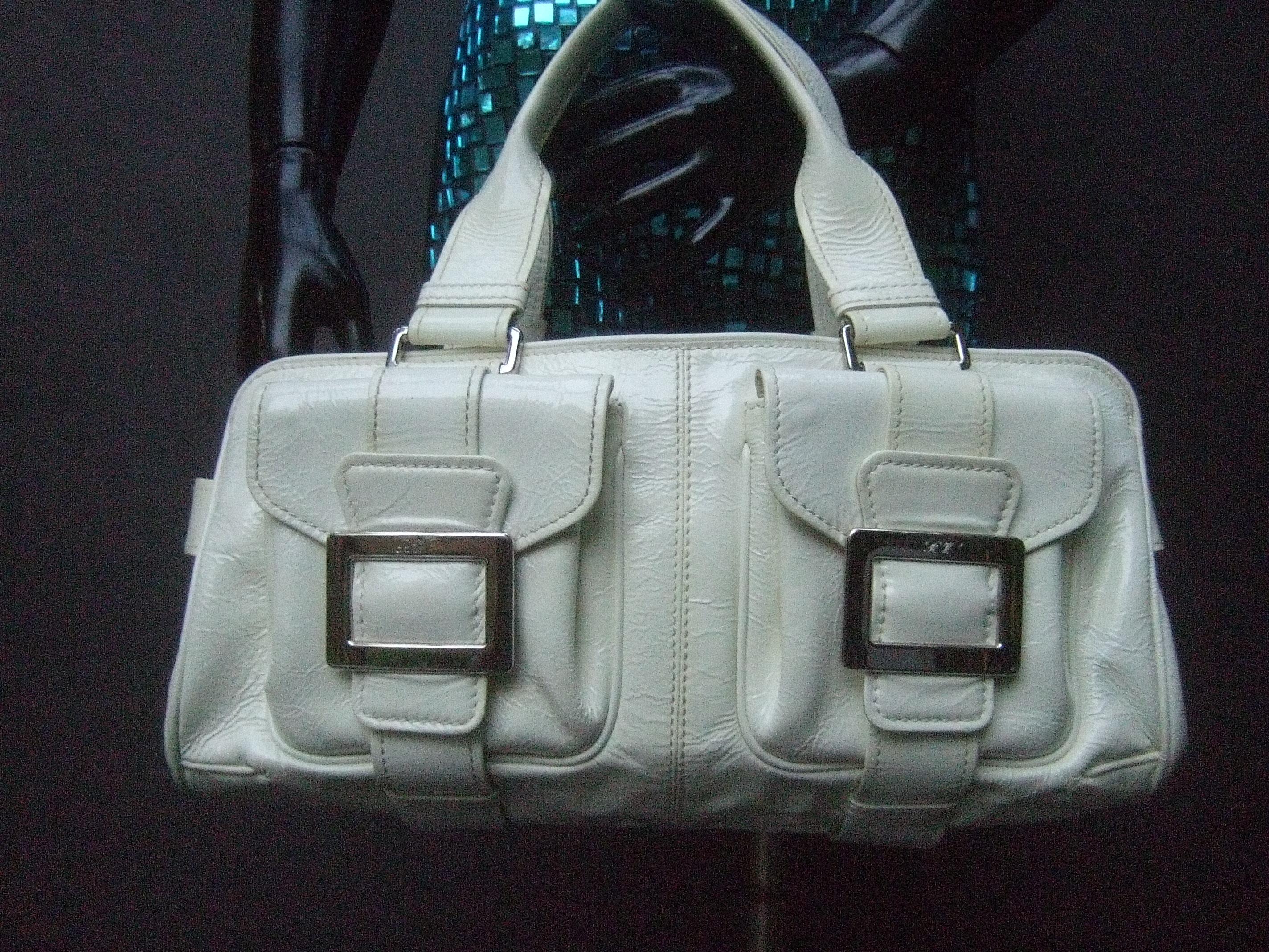 Roger Vivier Paris white patent leather chrome buckle Italian handbag c 1990s
The stylish handbag is designed with a pair of flap covered chrome buckle
pockets on the front exterior/ The pair of sleek chrome metal buckles are
engraved with Roger