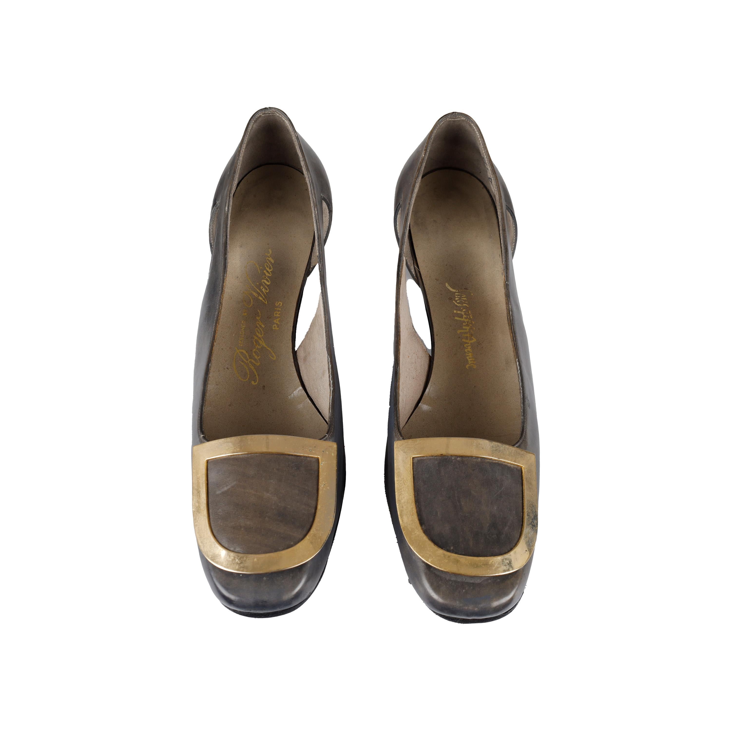 Queste décolleté con tacco a blocco di Roger Vivier, risalenti agli anni '60, saranno sicuramente il fiore all'occhiello di ogni look. Realizzate in colore grigio, la fibbia dorata e il taglio laterale aggiungono un'eleganza classica a queste