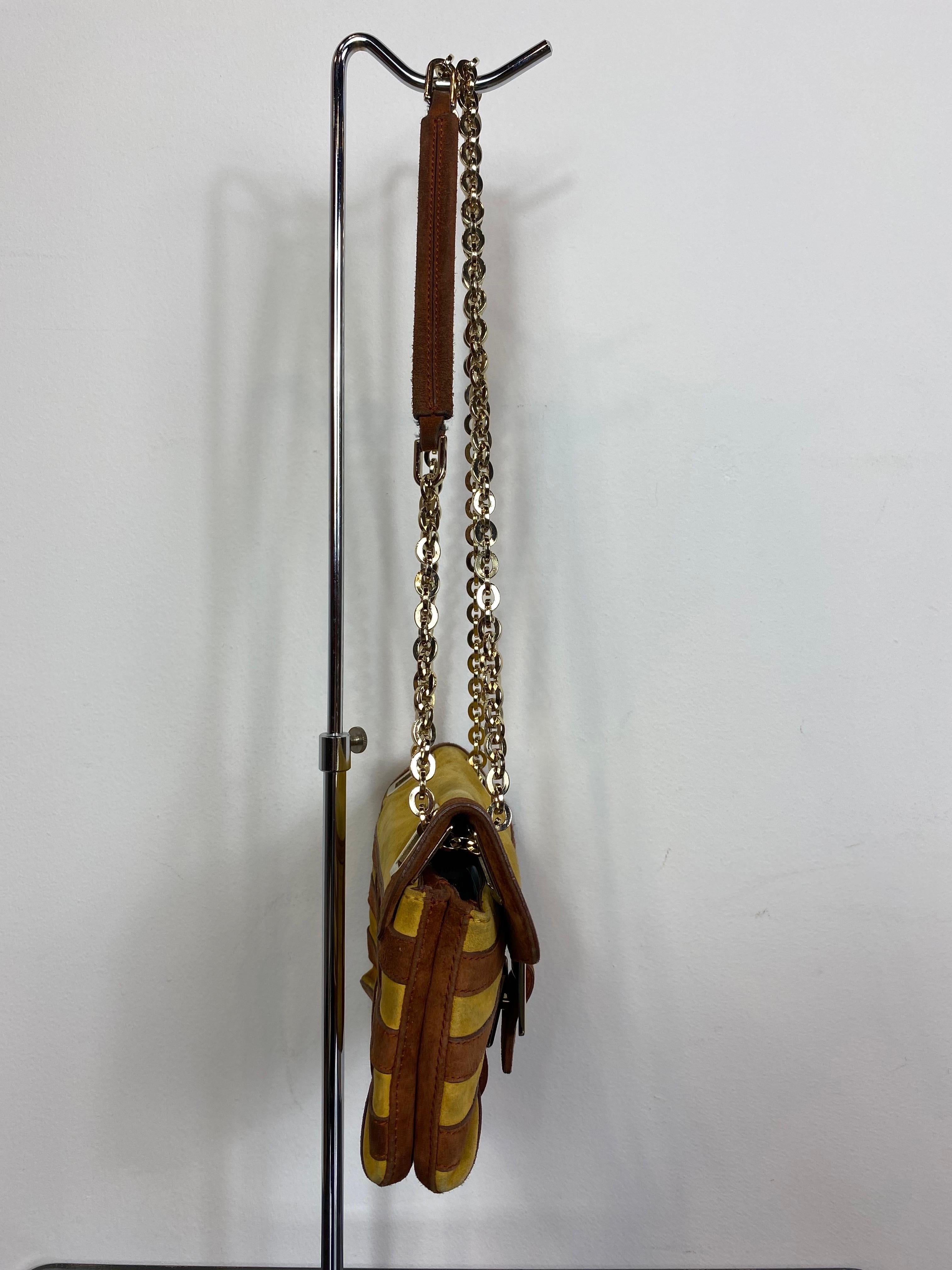 Roger Vivier Vintage shoulder bag in mustard and tan striped suede with gold metallic details and chain. 
Interlocking closure.
Equipped with three internal compartments, one of which has a zip closure. 
Internal pocket with zip and logoed