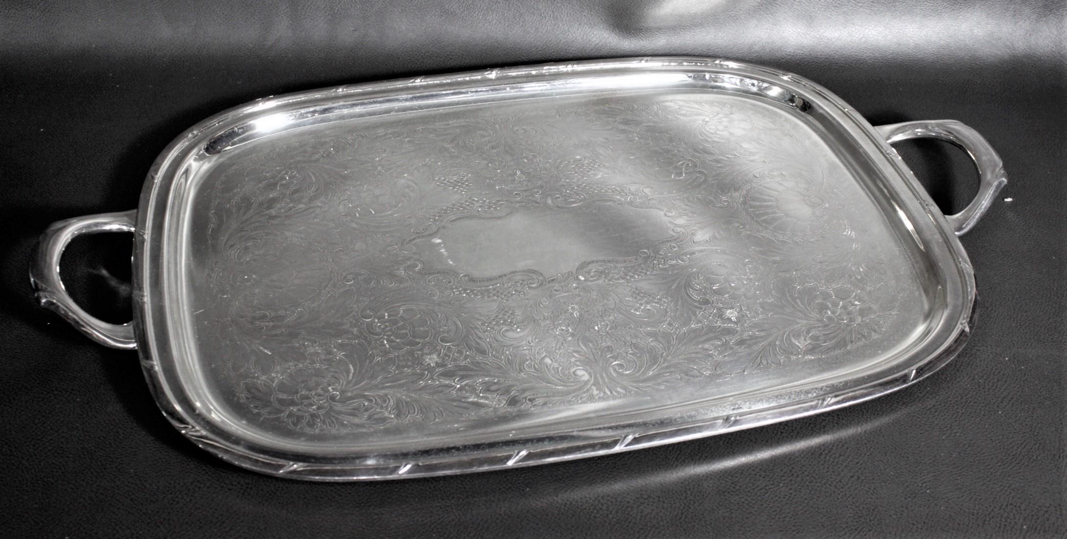 This silver plated serving tray was made by Rogers of Canada in approximately 1960 in an Edwardian antique style. The tray has a simple series of indentations around the raised outer rim, and considerable engraved scrollwork on the tray's surface.