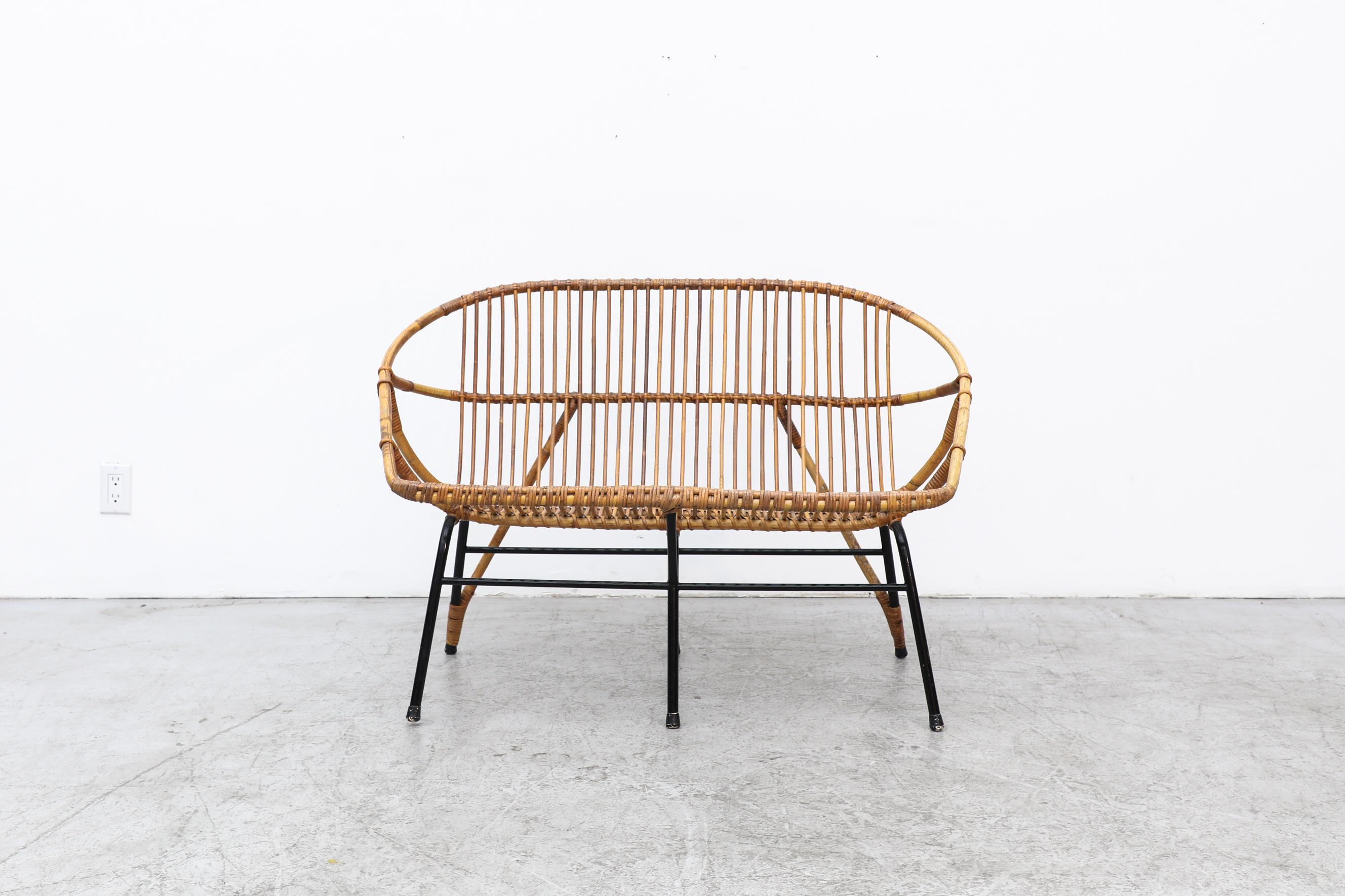 Delicately woven bamboo loveseat with rattan wrapped, black enameled, back legs. A gorgeous example of design by Dutch manufacturer Rohé Noordwolde in the 1960s. Rohé was one of the largest employers in the northern province of Friesland and in