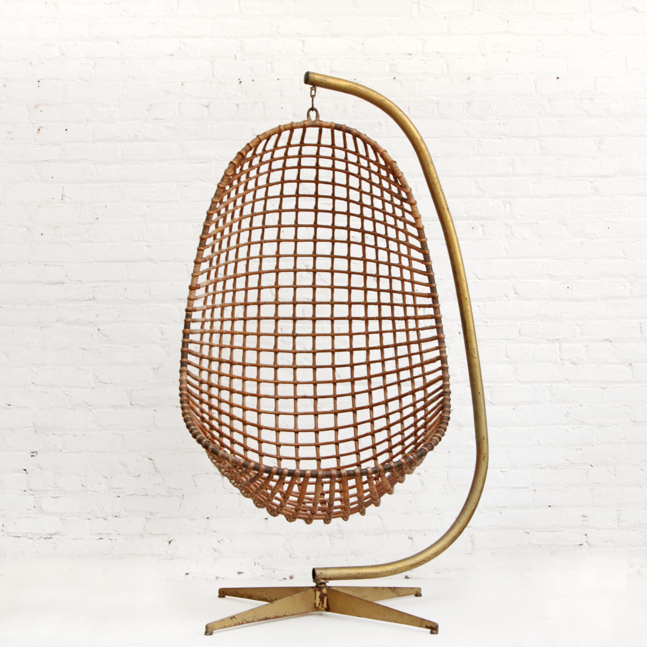 Rattan hanging egg chair on brass toned stand by Rohe Noordwolde, The Netherlands, 1960. Reinforced with iron cage and hanging point. Classic midcentury design, very well made. Swings and swivels comes with stand.