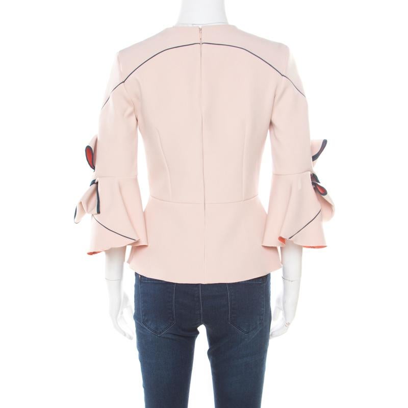 You'll definitely fall in love with this gorgeous blush pink top from Roksanda Illincic! It is made of a polyester blend and features a peplum silhouette. It flaunts a round neckline and an artistic bow detailing on the long sleeves. It comes