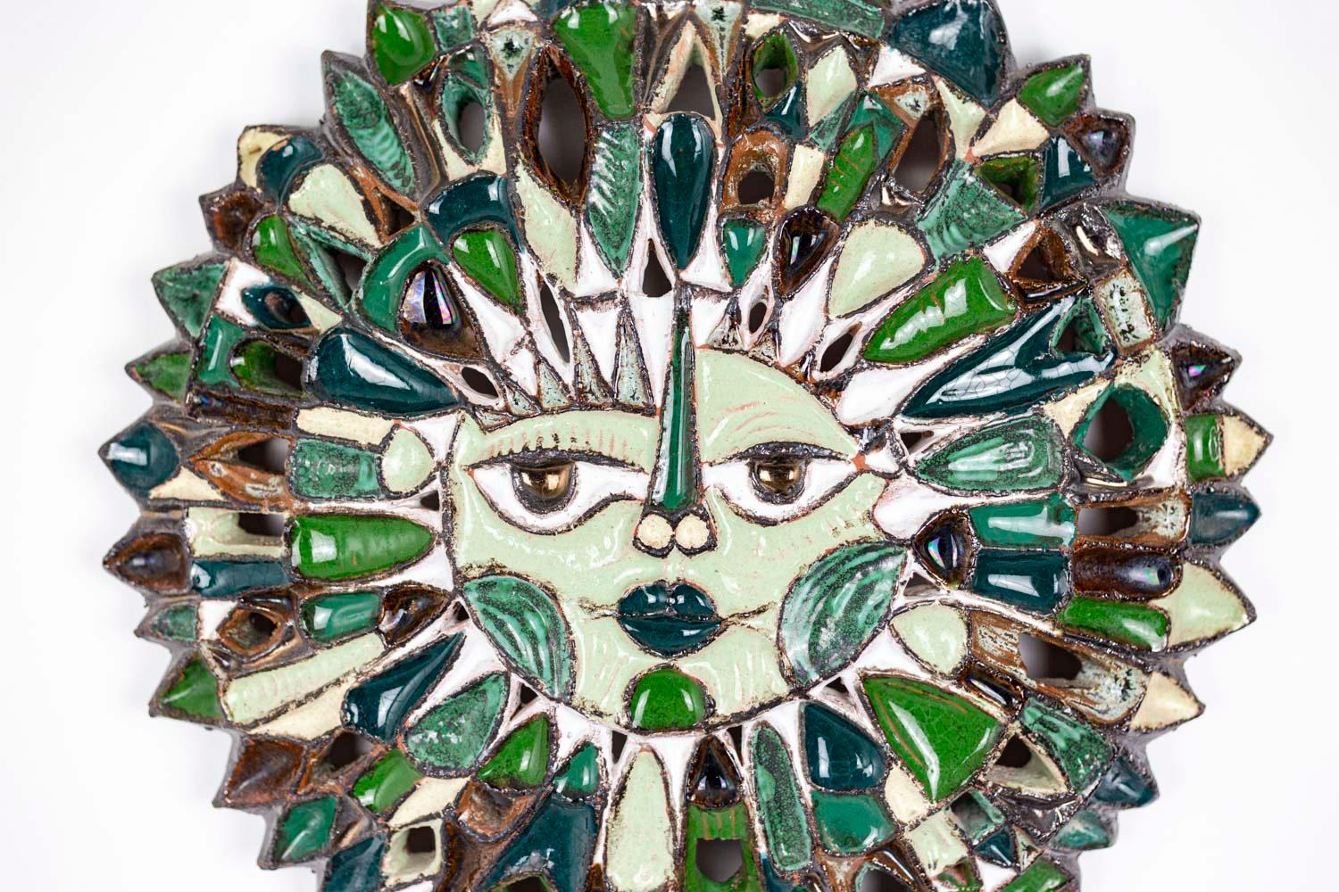 Roland Zobel, attributed to.

Sun-shaped mask in ceramic, with green-blue polychromed enamels. Central face highlighted with white enamel. Open spaces between the rays emanated from the face. 

Signed 