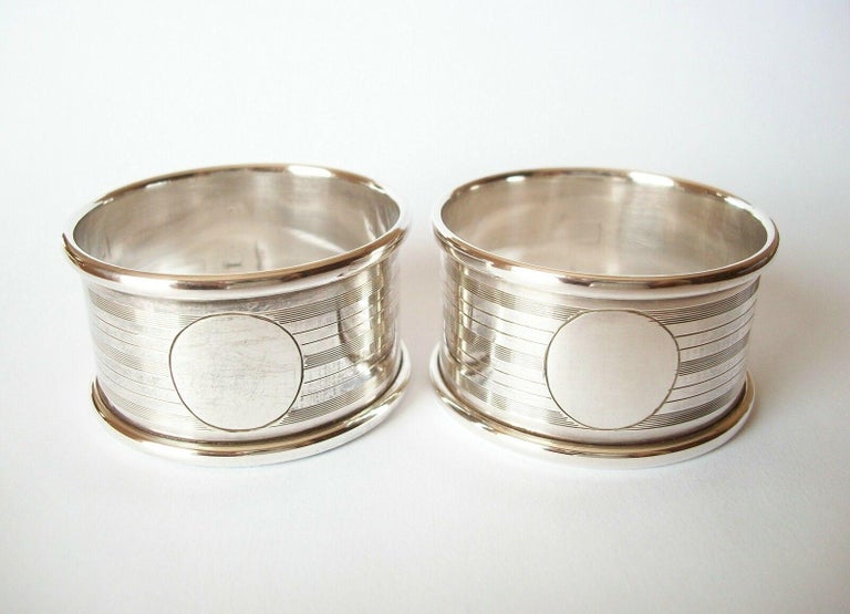 ROLASON BROTHERS (Vyse Street - Birmingham) - Art Deco pair of sterling silver napkin rings - each ring with engine turned design and a circular cartouche for an initial - each cartouche un-engraved - full British hallmarks for Birmingham - each