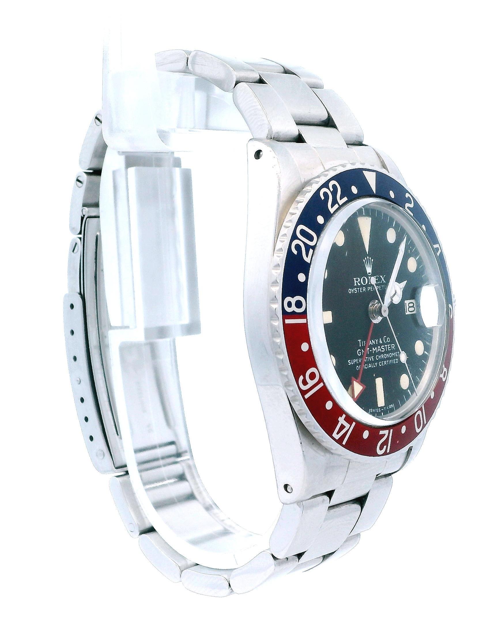Montre Rolex Oyster Perpetual Date GMT Master 1675. Boîtier fin en acier inoxydable de 40 mm. Lunette en acier inoxydable avec insert Pepsi. Cadran noir Tiffany avec aiguilles et index tritium en acier, index des minutes sur le pourtour du cadran.