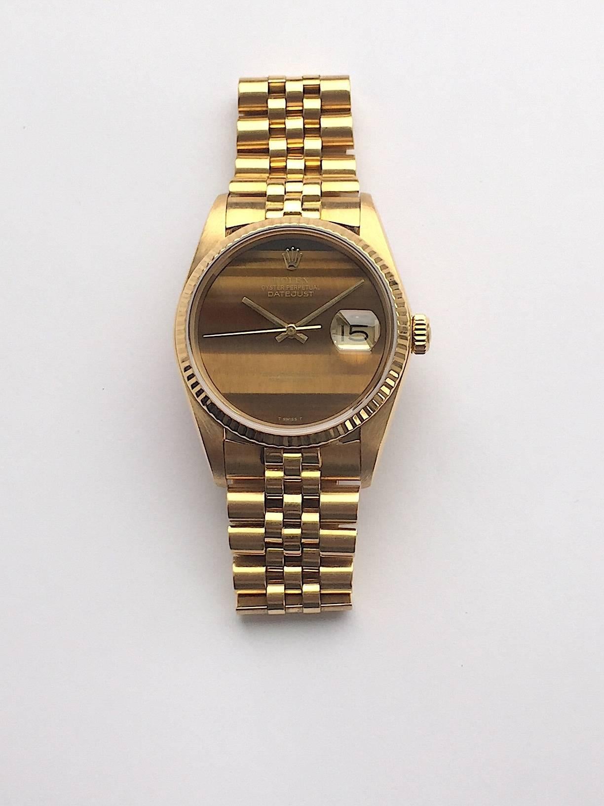 Rolex 18K Yellow Gold Oyster Perpetual Datejust Wristwatch
Factory Rolex Tiger's Eye Quartz Hard Stone Dial
Stunning Original Rolex Tiger's Eye Dial without Numerals 
Matching Hands to Dial 
18K Yellow Gold Fluted Bezel
36mm in size 
Rolex Calibre