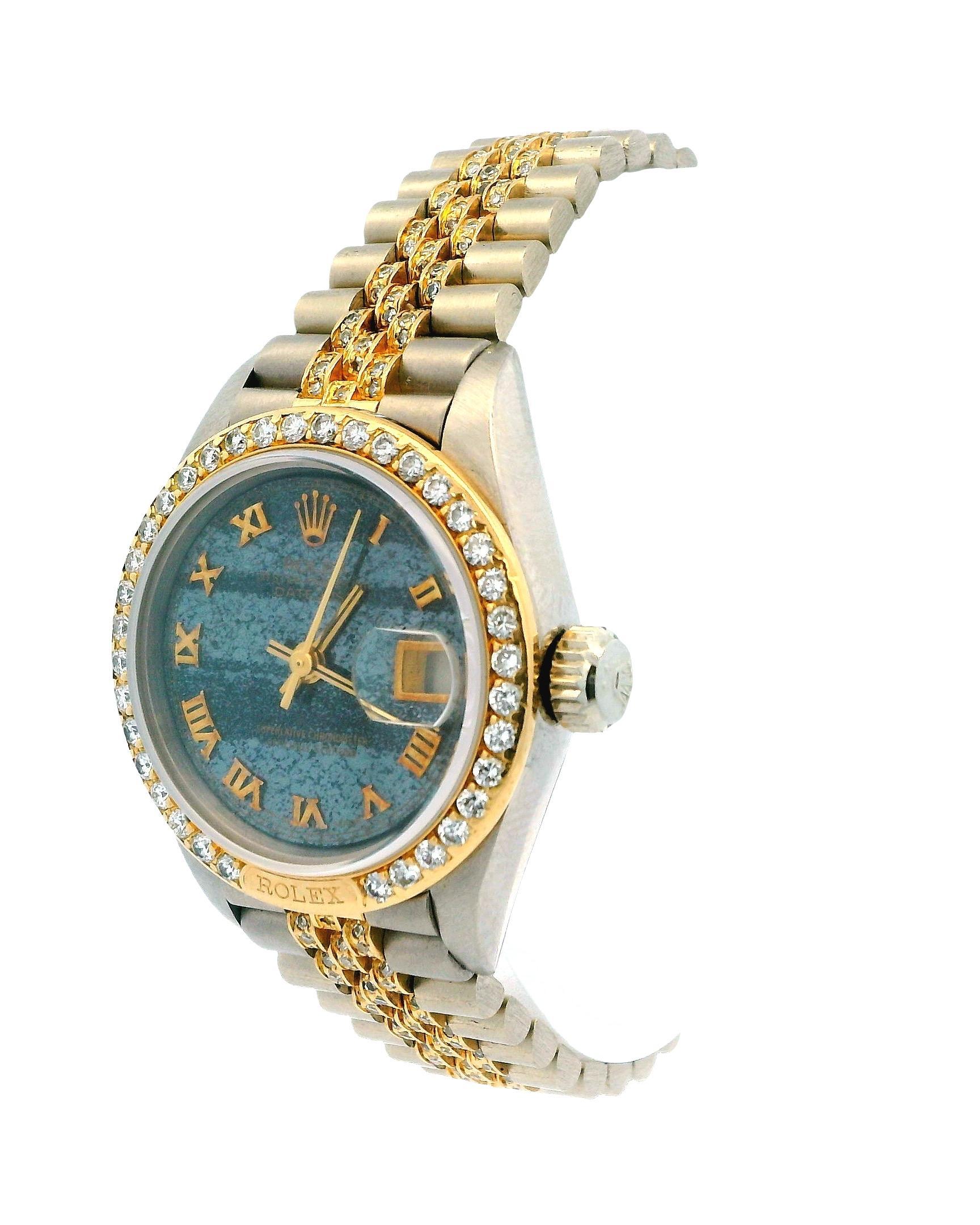 Die Rolex Lady-Datejust Ref. 69149 ist eine 26 mm große Uhr aus 18 Karat Weiß- und Gelbgold. Sie verfügt über ein seltenes Ferrit-Zifferblatt, ein Armband mit Pavé-Diamanten in der Mitte und eine vollständig mit Diamanten besetzte Lünette. Dieses