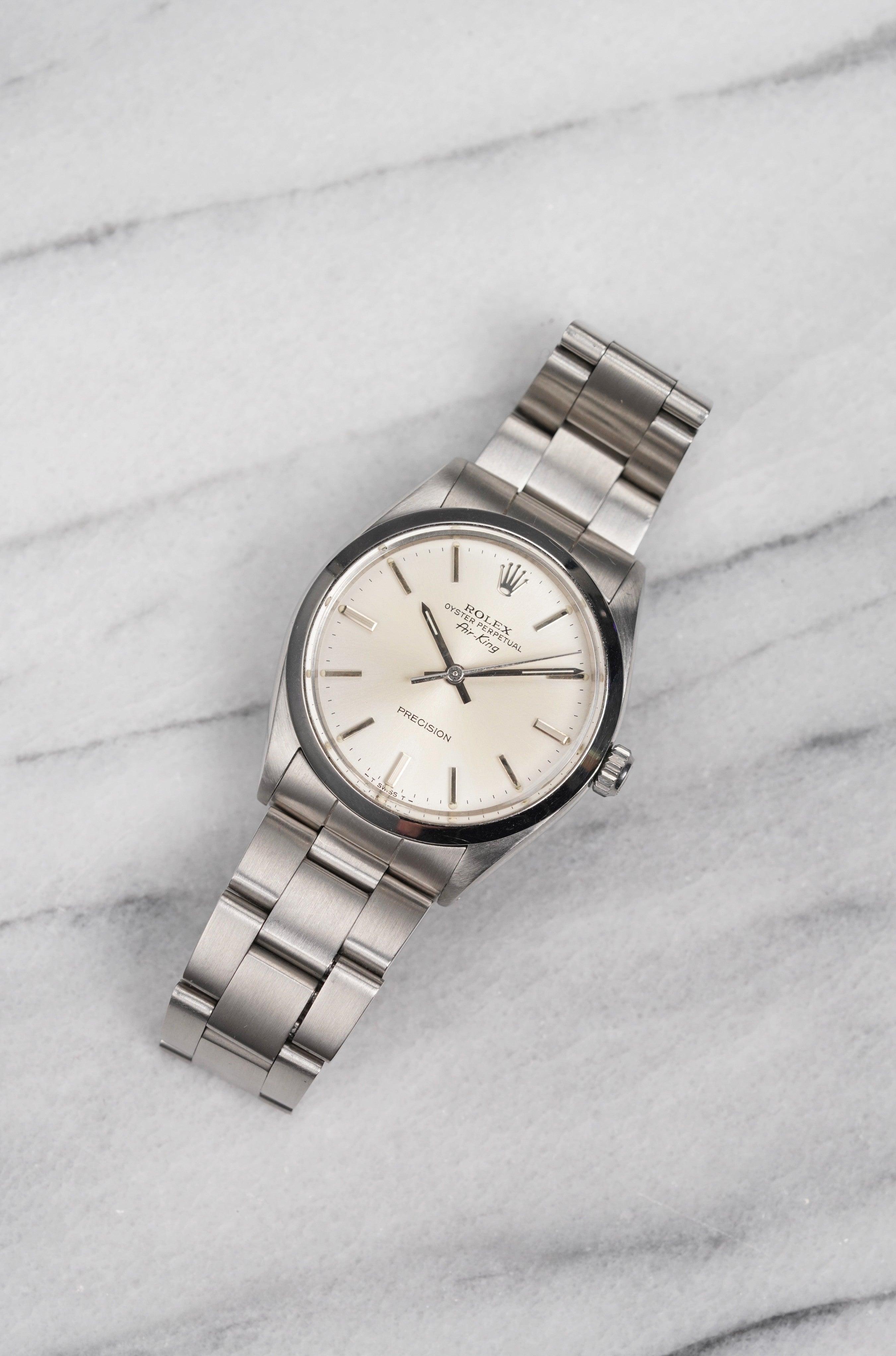 Aquí tienes un Rolex Air King vintage de precisión referencia 5500 automático con esfera crema plateada de los años 70. Mantiene la hora y es totalmente funcional. Las medidas incluyen una caja de ostra de 34 mm y una anchura de orejetas de 19 mm.