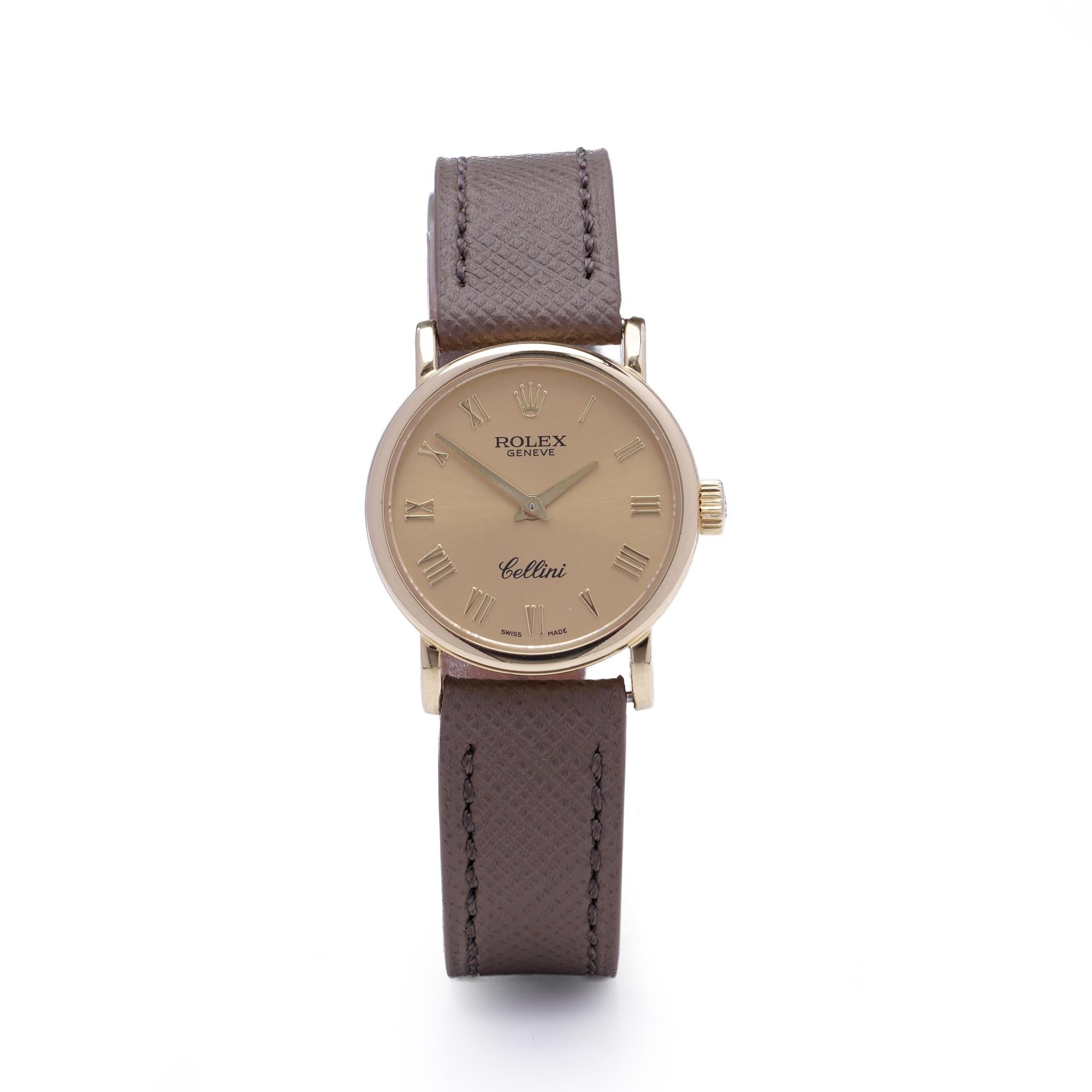 Rolex Cellini Damenarmbanduhr aus 18 Karat Gelbgold. Die Referenz 6110 hat ein rundes 25-mm-Gehäuse mit polierter Lünette und ein goldfarbenes/champagnerfarbenes Zifferblatt mit klassischen schwarzen römischen Ziffern. Die Uhr ist mit einem braunen
