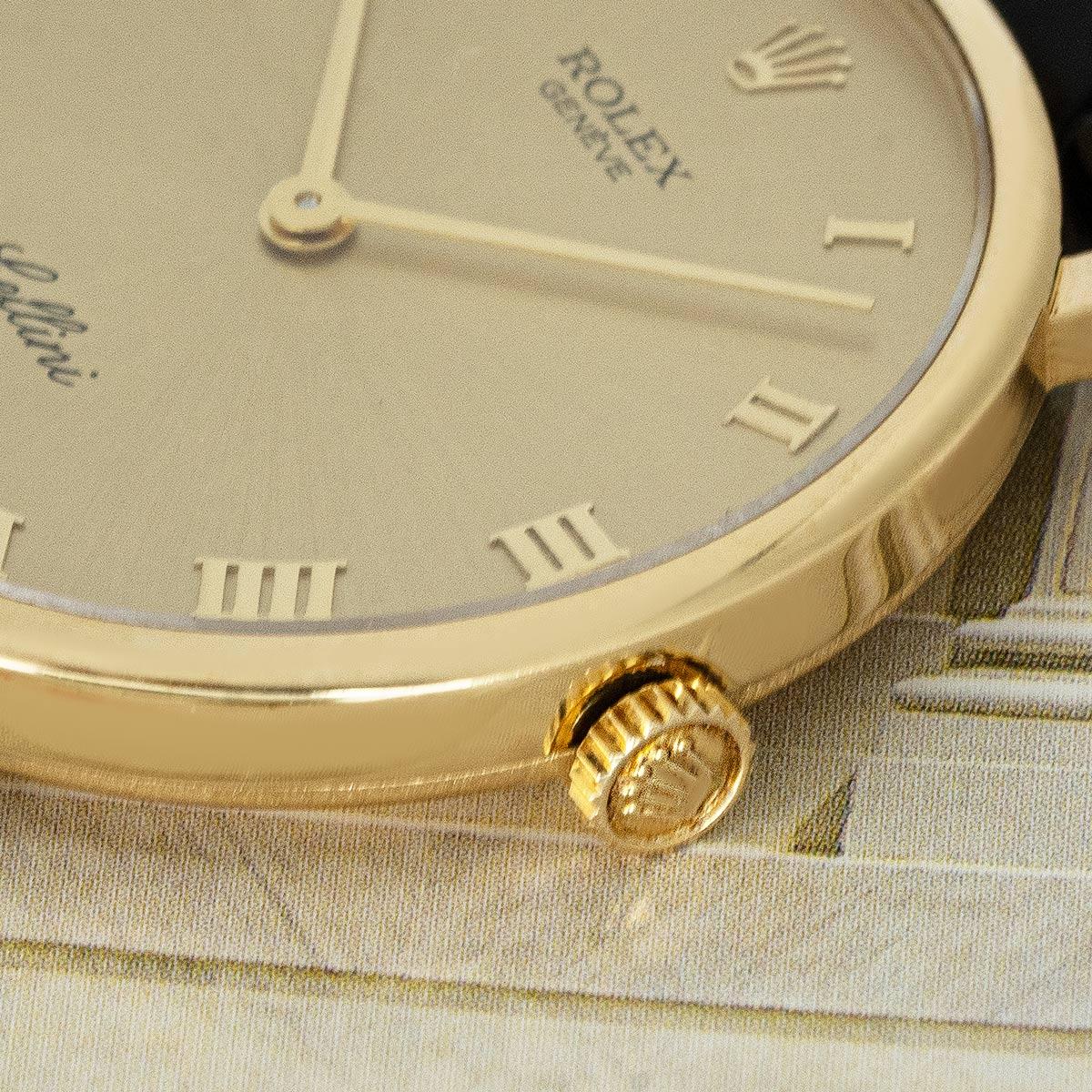 A Cellini wristwatch in yellow gold by Rolex. Features a champagne dial with Roman numerals. Fitted with sapphire glass and a manual wind movement. The piece is presented on a new generic black leather strap which is equipped with a yellow gold