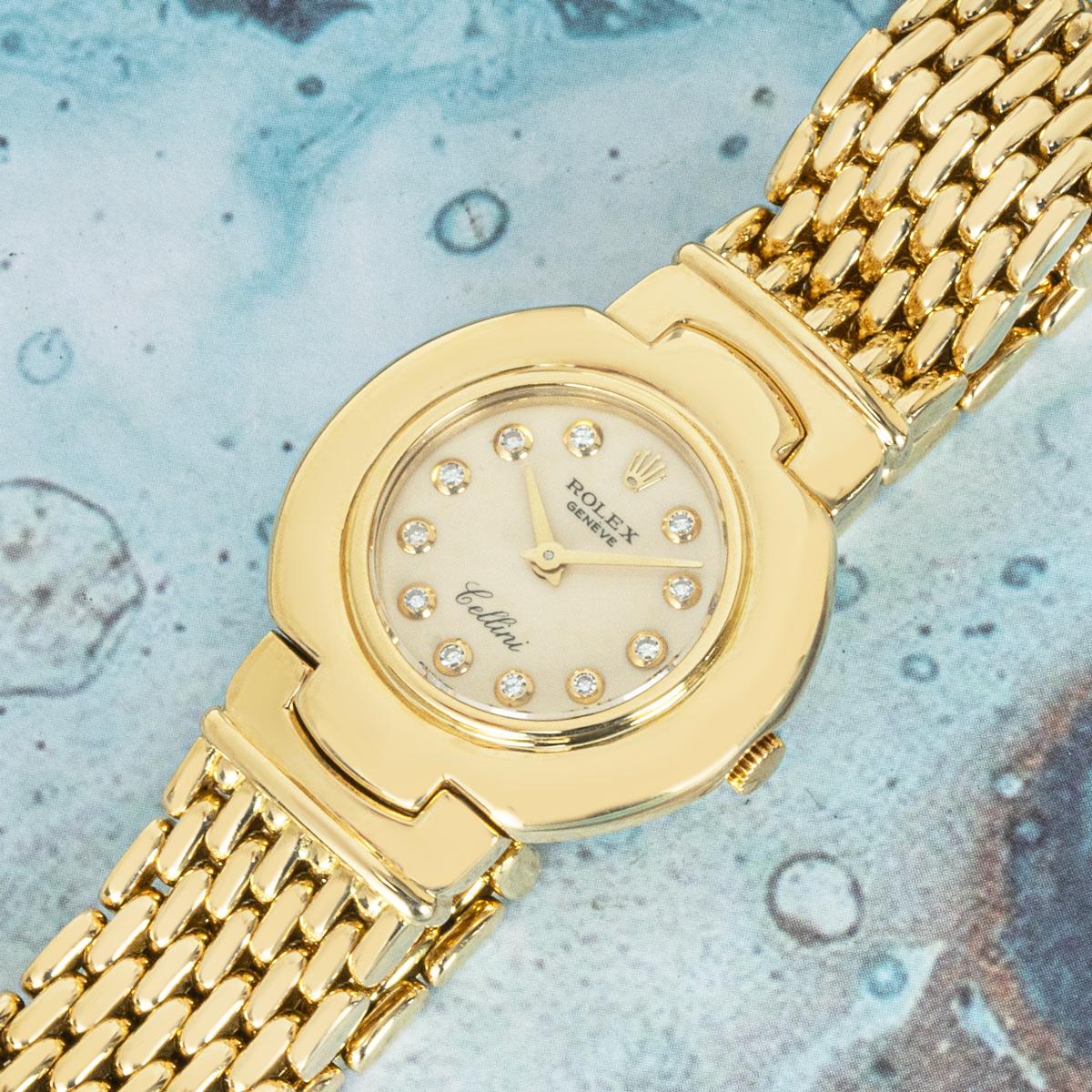 Une montre-bracelet Cellini en or jaune de Rolex. Cadran argenté avec index sertis de diamants et lunette lisse en or jaune. La montre est équipée d'un bracelet intégré et d'une boucle déployante, tous deux également en or jaune. Elle est équipée
