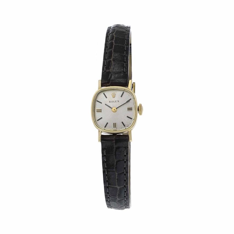 This is a classic Rolex women's watch from 1980. The case is 14K yellow gold and measures 17mm square.
The dial of the watch is silver in color with non numeric stick hour markers. 
The watch is powered by a Rolex caliber 1401 17 jewel manual wind