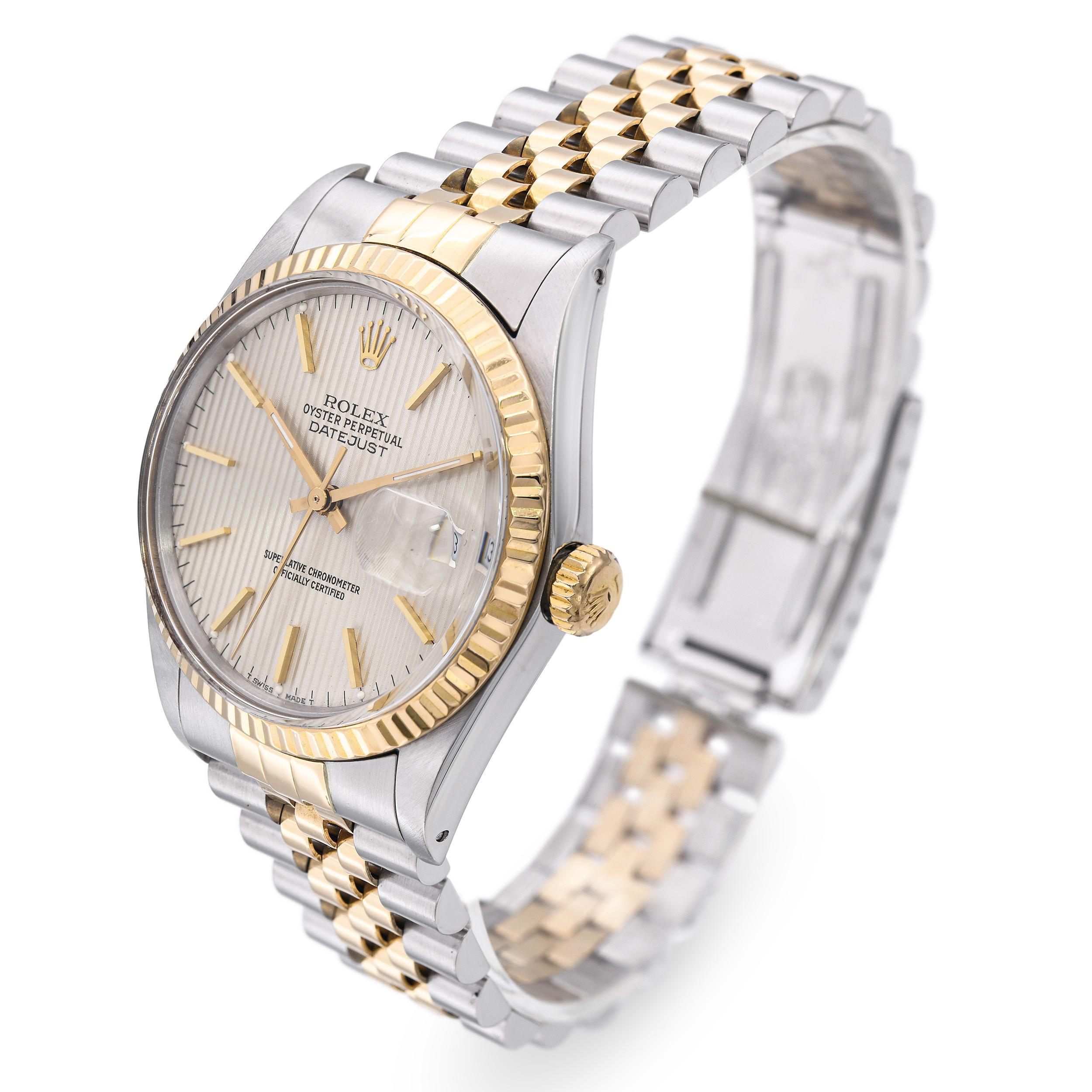 Diese Rolex Datejust 16013 kombiniert Edelstahl und 18 Karat Gelbgold mit einem auffälligen silbernen Gobelin-Zifferblatt, das für sein einzigartiges vertikales Strukturmuster bekannt ist. Das 36-mm-Gehäuse verfügt über die klassische geriffelte