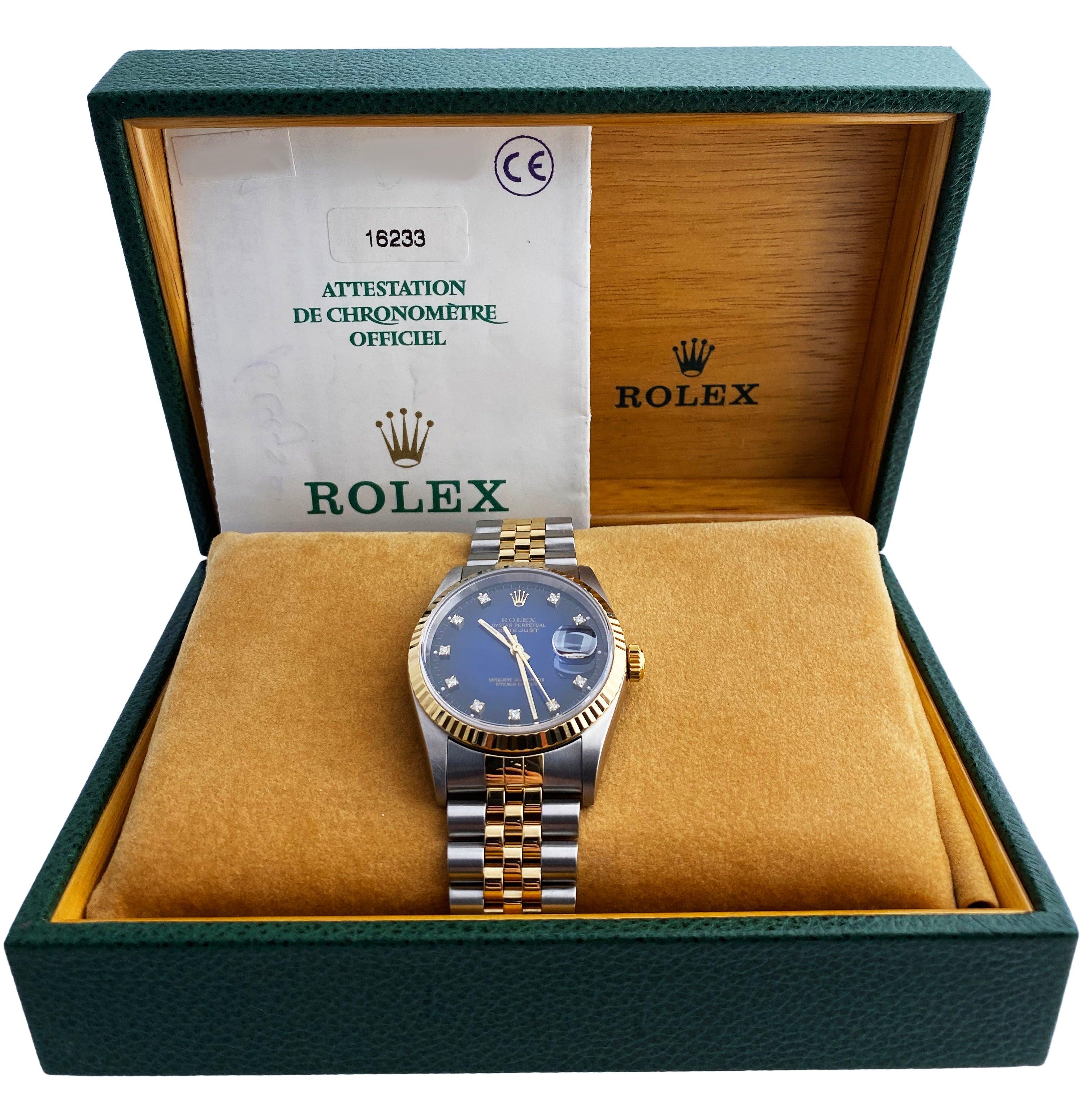 
Rolex Datejust 16233 Men's Watch. 36mm stainless steel case. 18k yellow gold fluted bezel. Blue dial with gold luminous hands. Original factory diamond set hour markers. Minute markers on the outer dial. Date display at the 3 o'clock position.