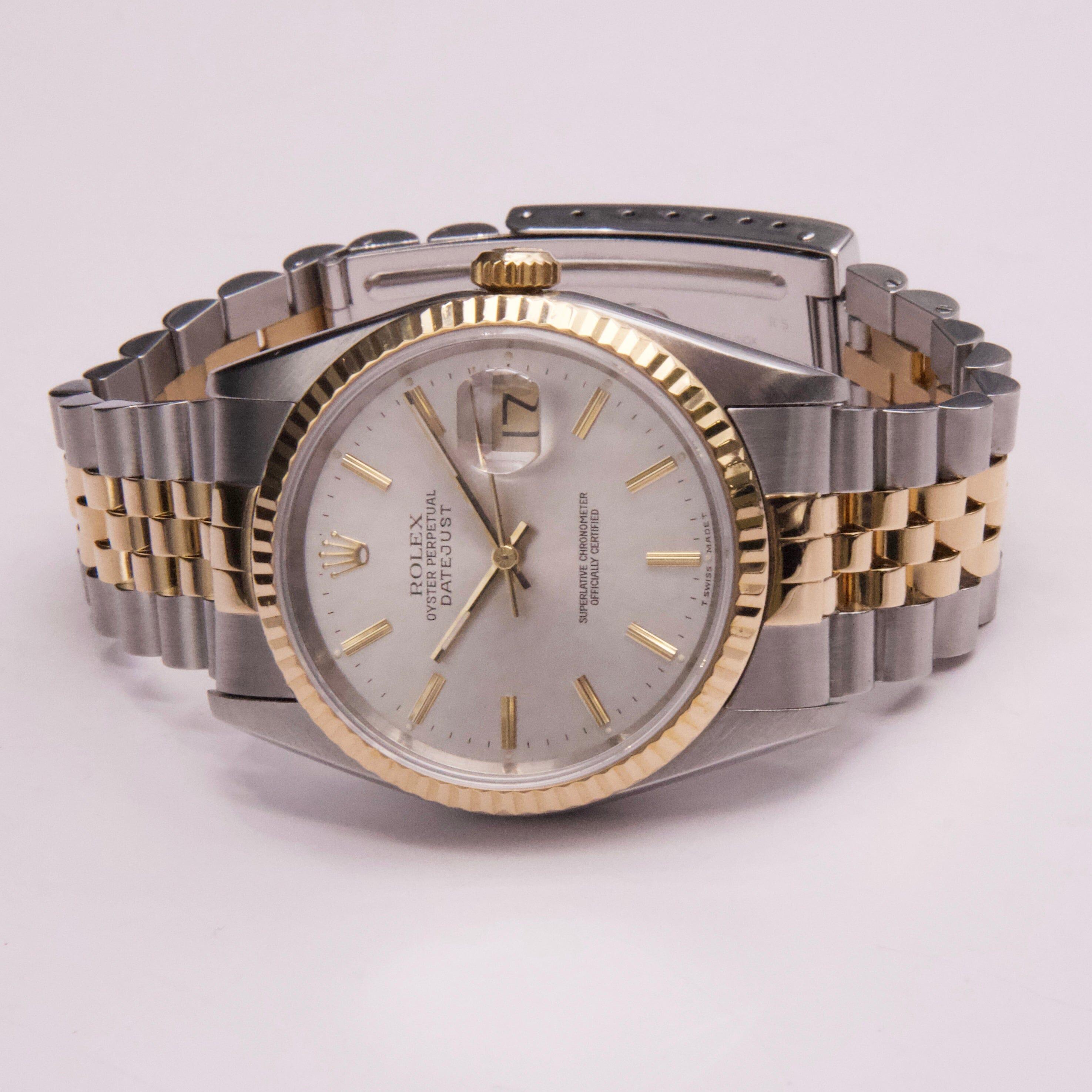 Rolex Datejust 16233 Herrenuhr. 36-mm-Edelstahlgehäuse. 18K Gelbgold geriffelte Lünette. Silbernes Zifferblatt mit goldenen Zeigern und goldenen Indexen. Minutenmarkierungen auf dem äußeren Zifferblatt. Datumsanzeige auf der 3-Uhr-Position.