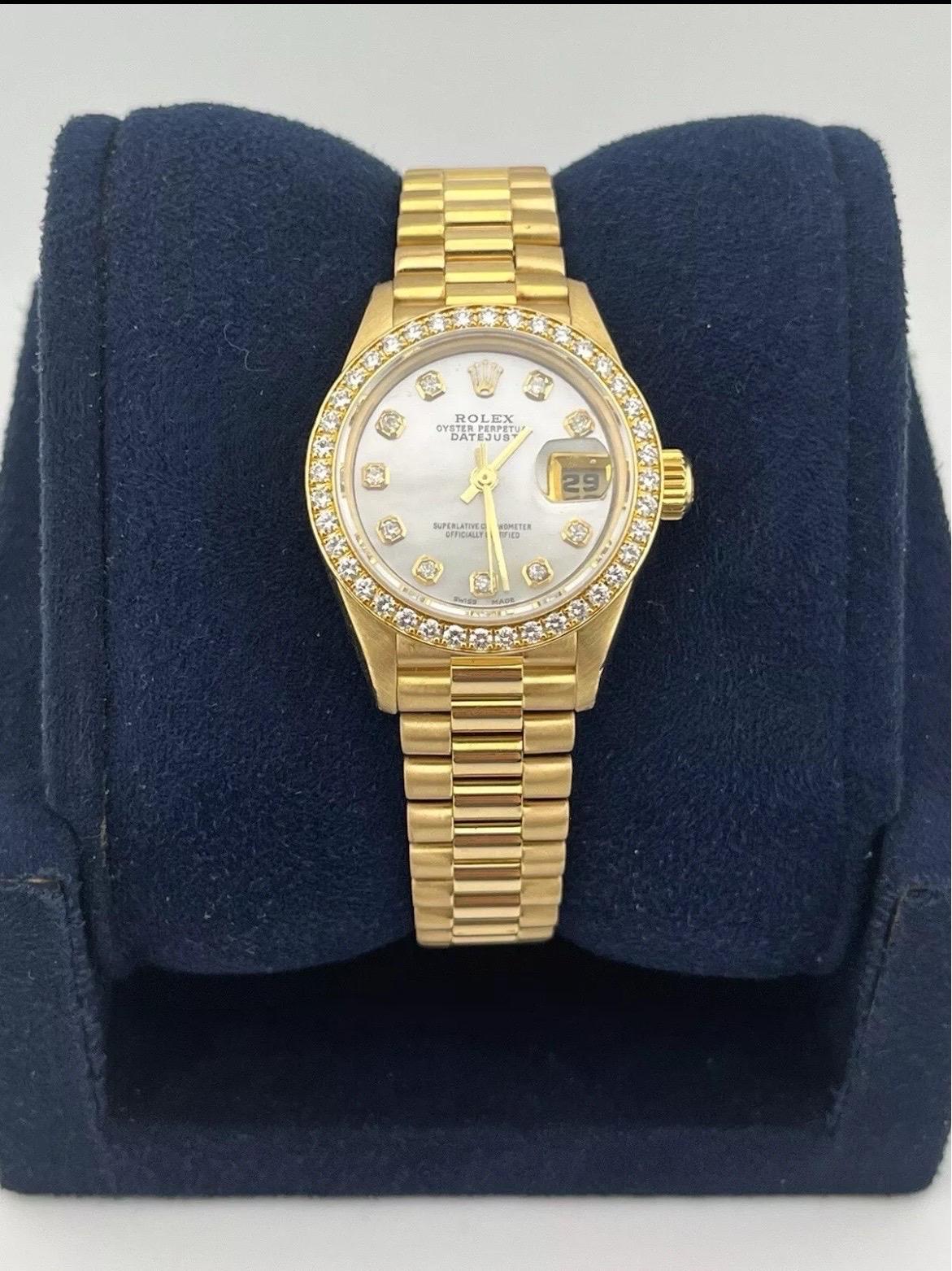 The Rolex Datejust 18K Gold President 69138 Diamond Bezel MOP Dial Ladies 26mm Watch is a quintessential symbol of luxury and refinement. Crafted in 18K yellow gold, this elegant timepiece features the iconic President bracelet, renowned for its