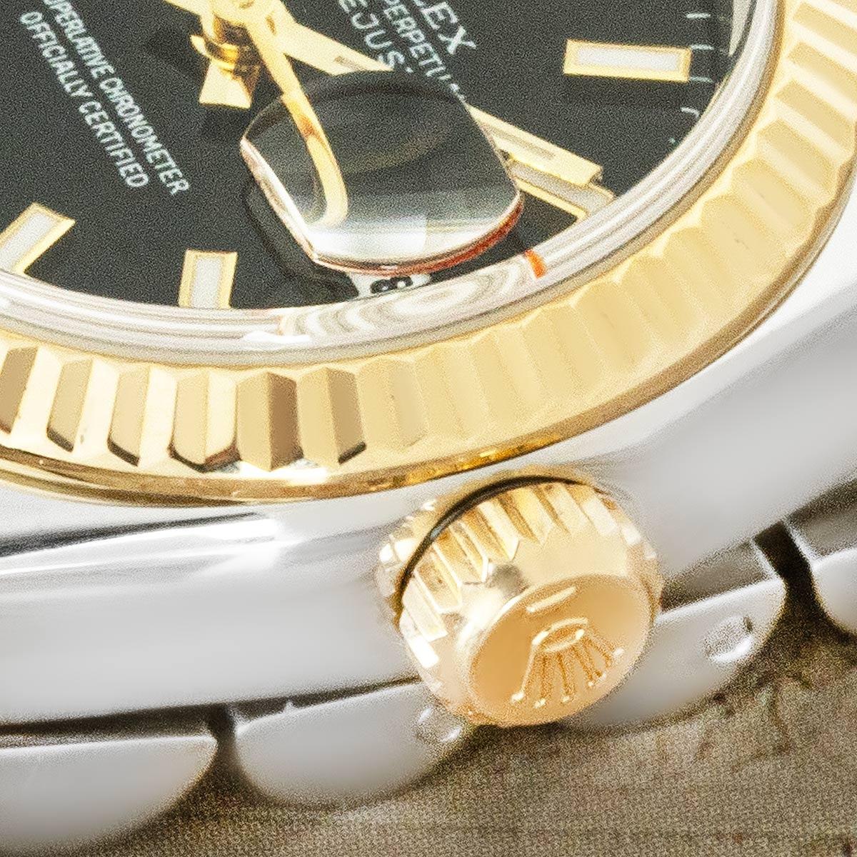 A ladies stainless steel and yellow gold 26mm Datejust by Rolex. Featuring a black dial and a yellow gold fluted bezel. Fitted with sapphire crystal and a self-winding automatic movement, this piece is presented on a Jubilee bracelet equipped with a
