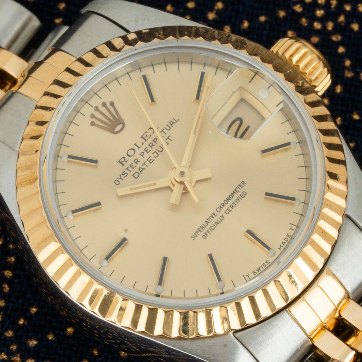 Eine 26-mm-Datejust aus Edelstahl und Gelbgold von Rolex. Das champagnerfarbene Zifferblatt wird durch eine kannelierte Lünette aus Gelbgold ergänzt. Das Jubiläumsarmband ist mit einer Oyster Faltschließe ausgestattet. Ausgestattet mit Saphirglas