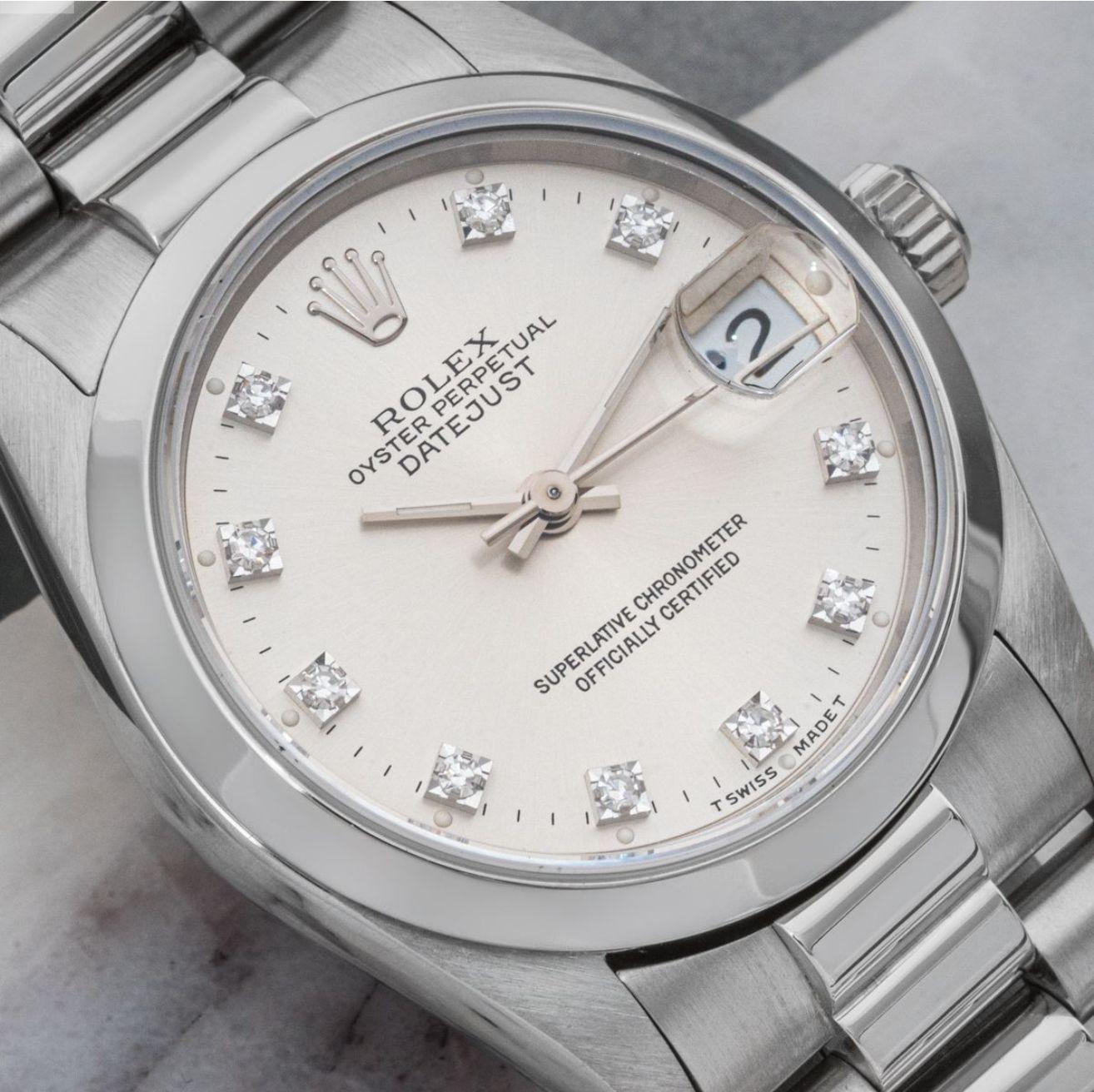 A midsize platinum Datejust by Rolex. Featuring a silver dial with diamond set hour markers and a smooth platinum bezel. The president bracelet is fastened by a concealed folding Crownclasp. The watch is also fitted with a sapphire crystal and a