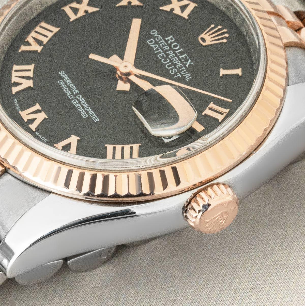 A 36mm Datejust in stainless steel and rose gold by Rolex. Featuring a black sunbeam dial with Roman numerals and a fluted rose gold bezel. The watch is presented on a Jubilee bracelet which is equipped with a concealed folding clasp. Fitted with
