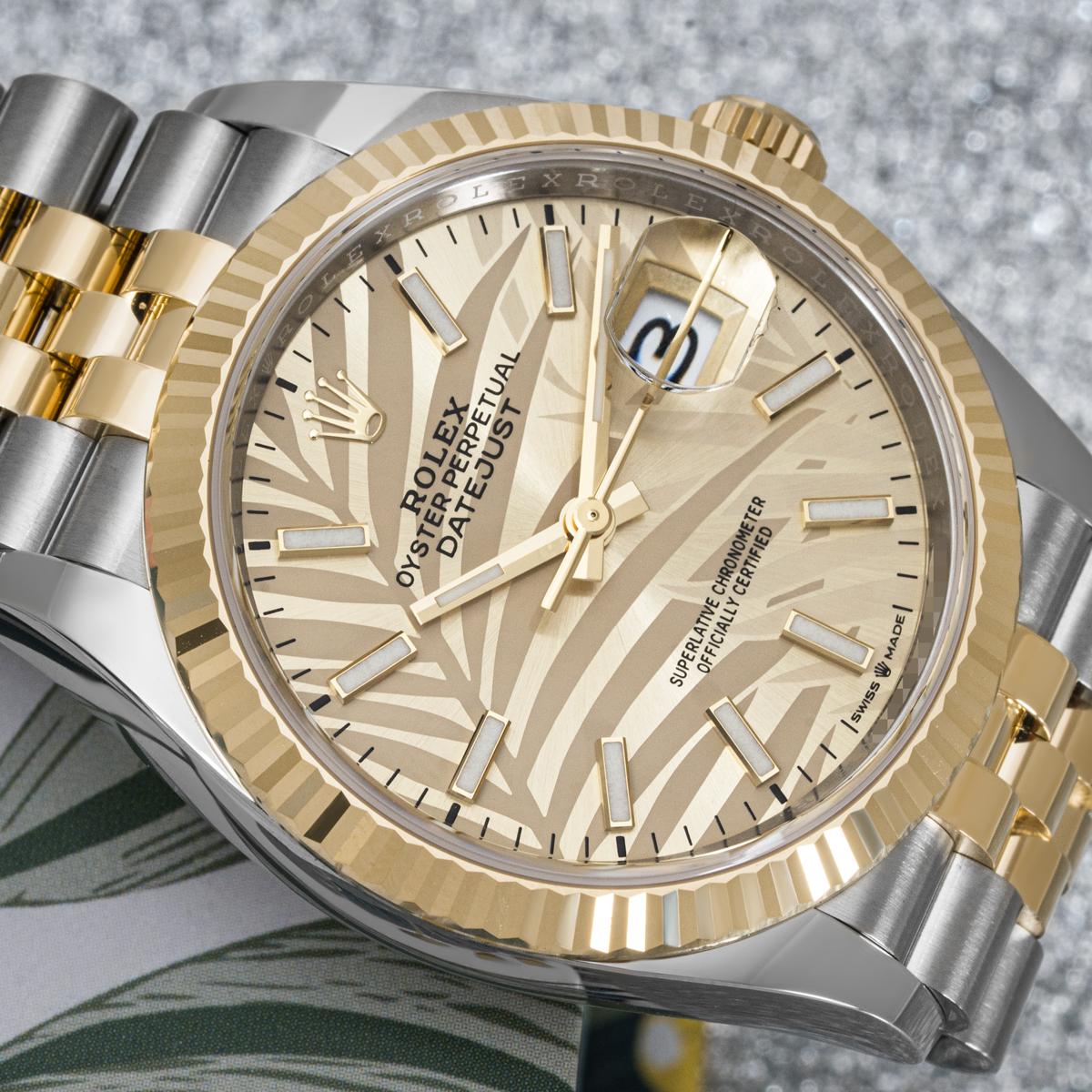 A 36mm stainless steel and yellow gold Datejust by Rolex. Featuring a champagne palm motif dial with applied hour markers. Fitted with a sapphire glass and a self-winding automatic movement. The watch is also equipped with a steel and yellow gold