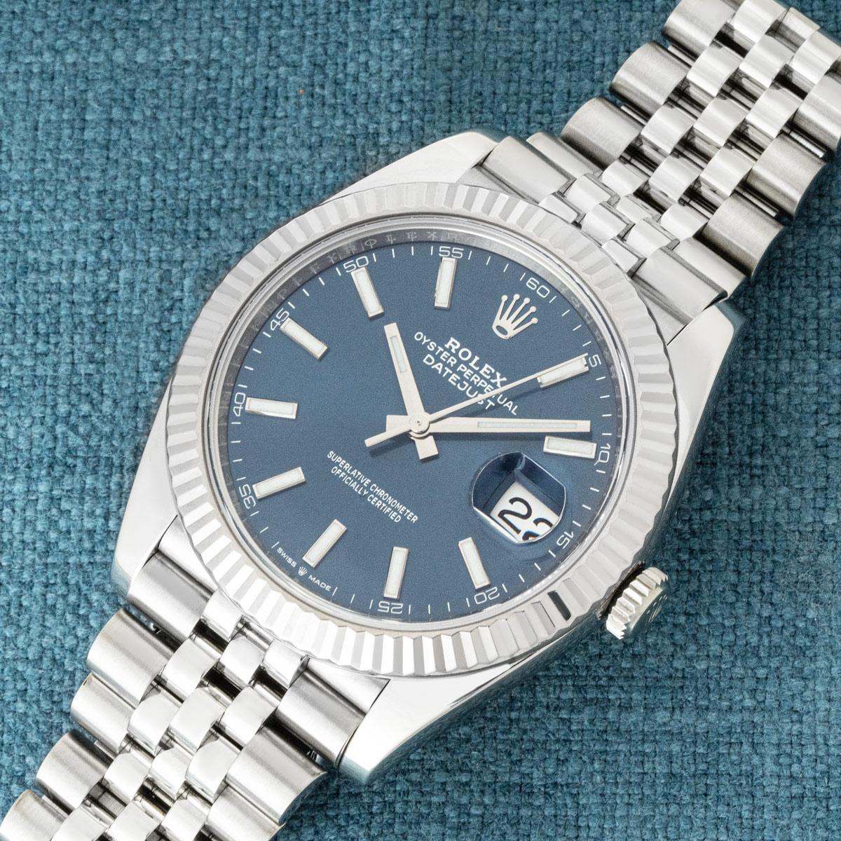 A stainless steel Datejust 41 by Rolex. Features a blue dial with applied hour markers, complemented by a white gold fluted bezel. The watch is fitted with scratch-resistant sapphire crystal, a self-winding automatic movement, and a Jubilee bracelet