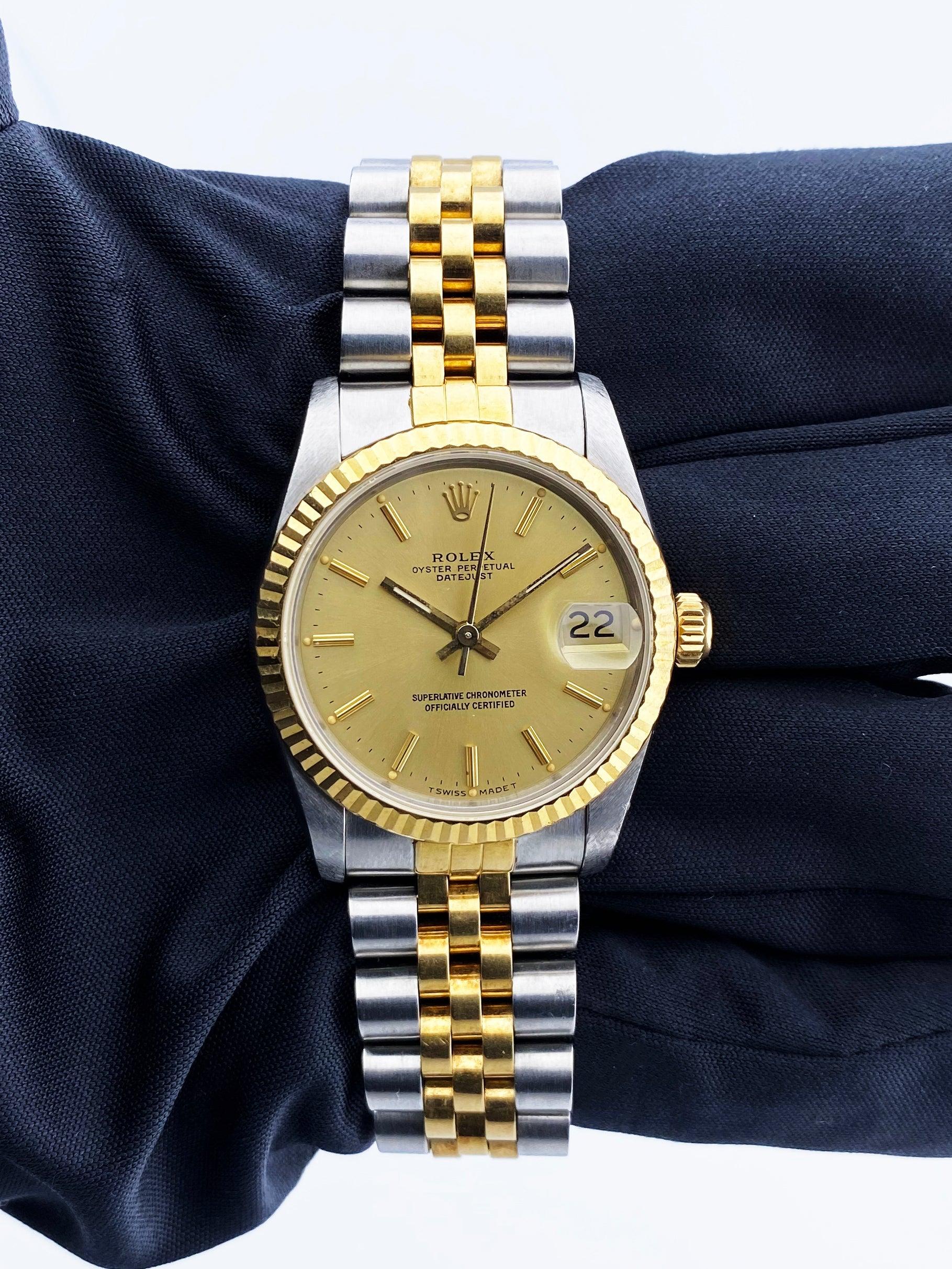 Rolex Datejust 68273 Ladies Watch. 31mm stainless steel case. 18K yellow gold fluted bezel. Champagne dial with gold hands and index hour markers. Minute markers on the outer dial. Date display at the 3 o'clock position. Stainless steel & 18K yellow