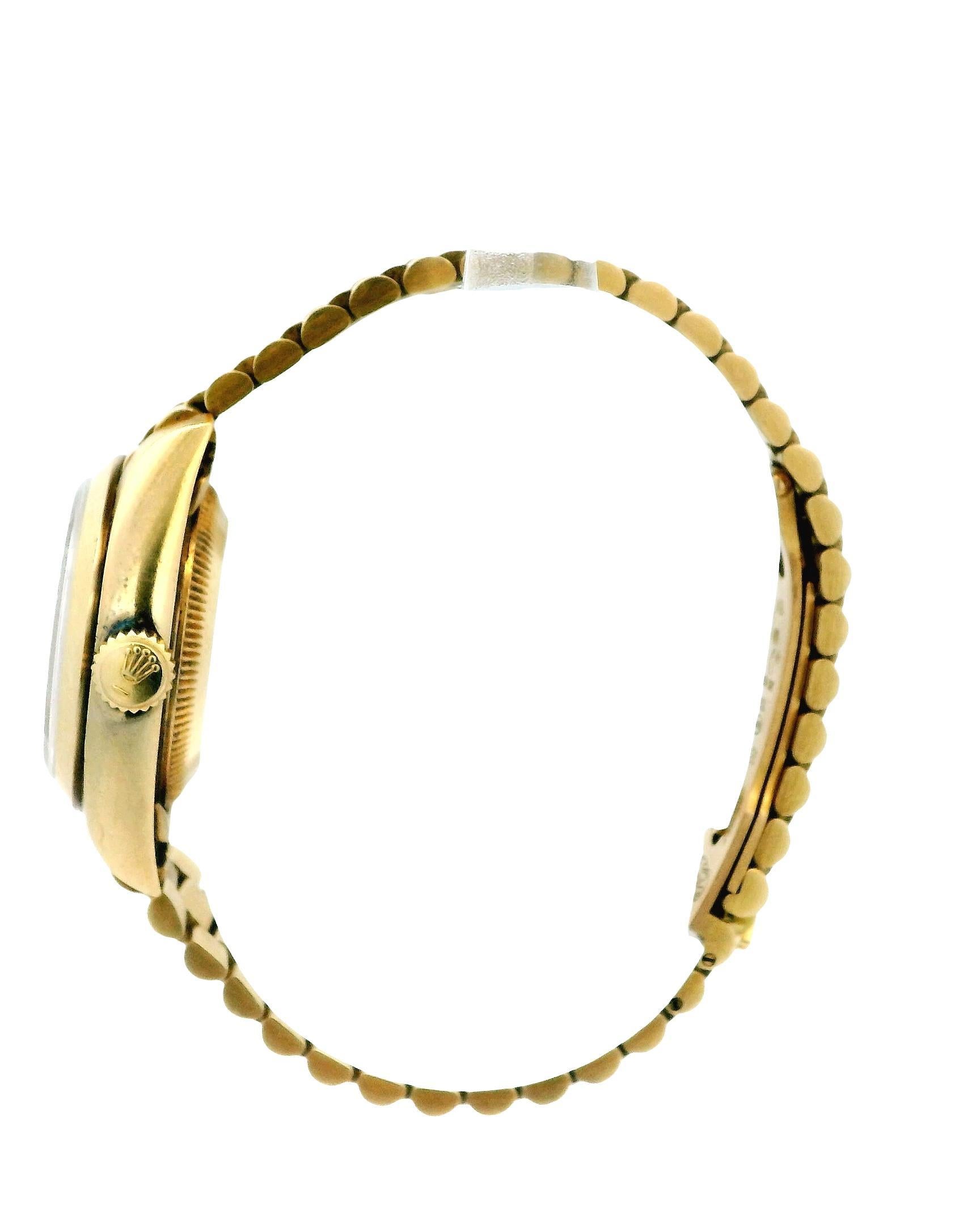 Montre pour dames Rolex Datejust 69168. Cet élégant garde-temps est doté d'un boîtier de 26 mm en or jaune 18 carats et d'une lunette lissée réalisée dans le même matériau. Le cadran blanc est complété par des aiguilles en or et des index en
