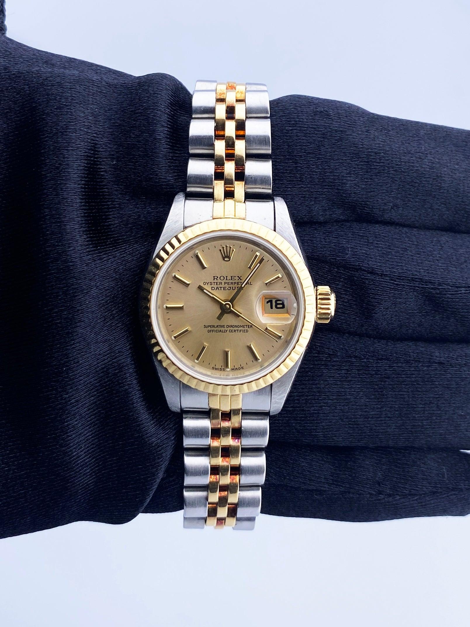 Rolex Datejust 69173 Ladies Watch. 26mm stainless steel case with 18K yellow gold fluted bezel. Champagne dial with gold hands and index hour markers. Minute markers on the outer dial. Date display at the 3 o'clock position. Stainless steel & 18K