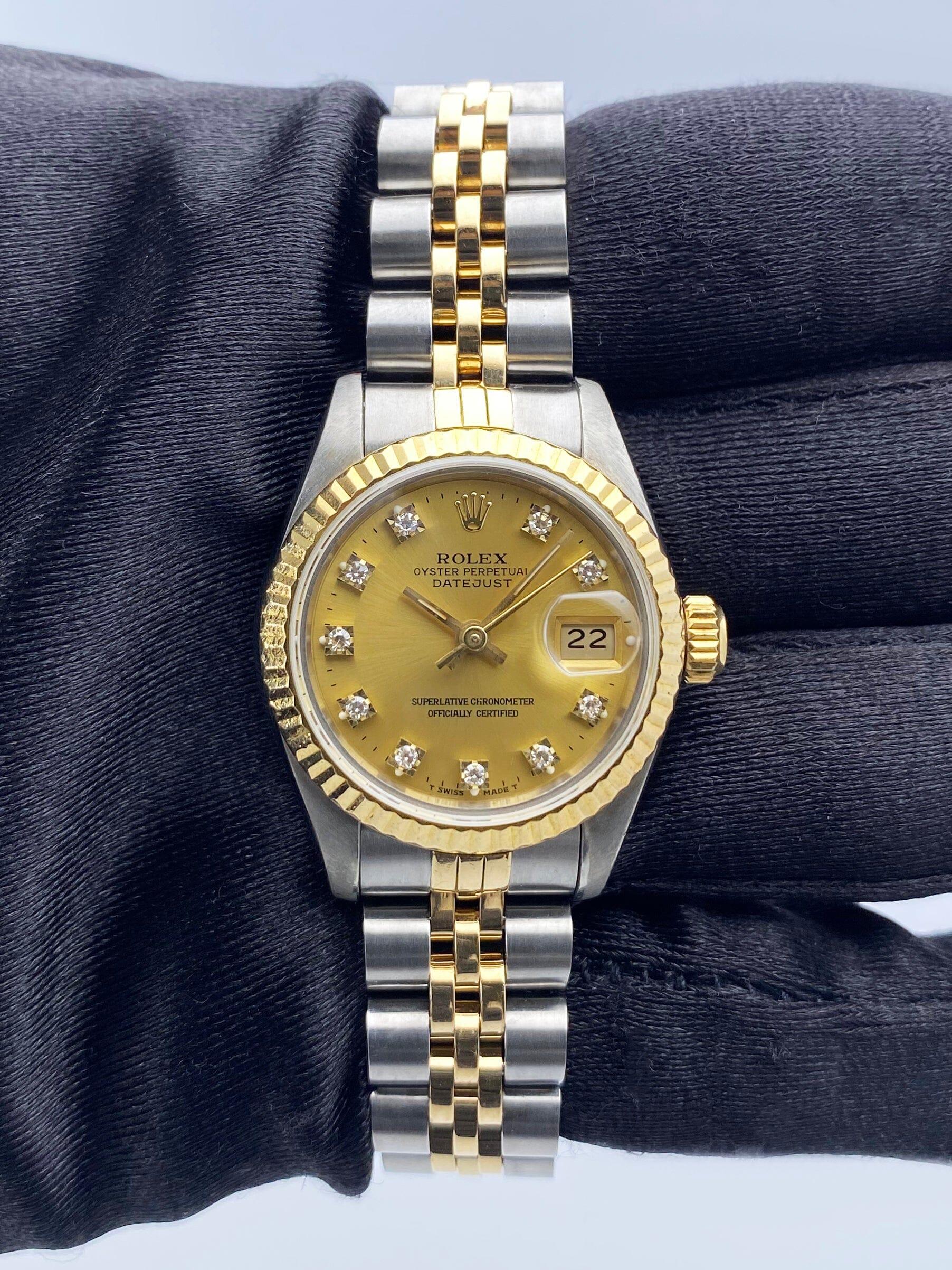 Rolex Datejust 69173 Ladies Watch. 26mm stainless steel case. 18K yellow gold fluted bezel. Champagne dial with gold hands and factory diamond hour markers. Minute markers on the outer dial. Date display at the 3 o'clock position. Stainless steel