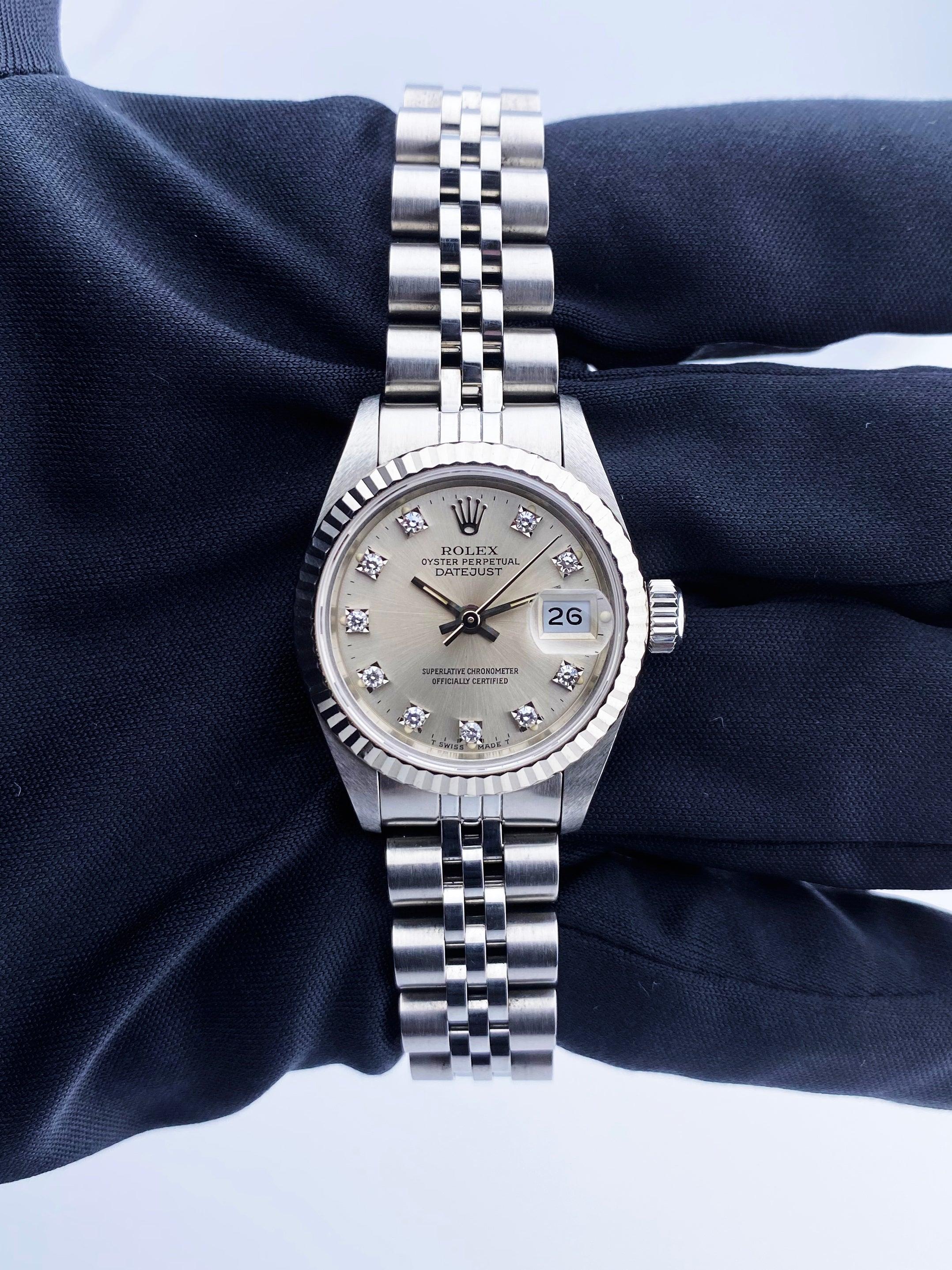 
Rolex Datejust 69174 Ladies Watch. 26mm stainless steel case with 18K white gold fluted bezel. Silver dial with luminous steel hands and original factory diamond set hour markers. Minute markers on the outer dial. Date display at the 3 o'clock
