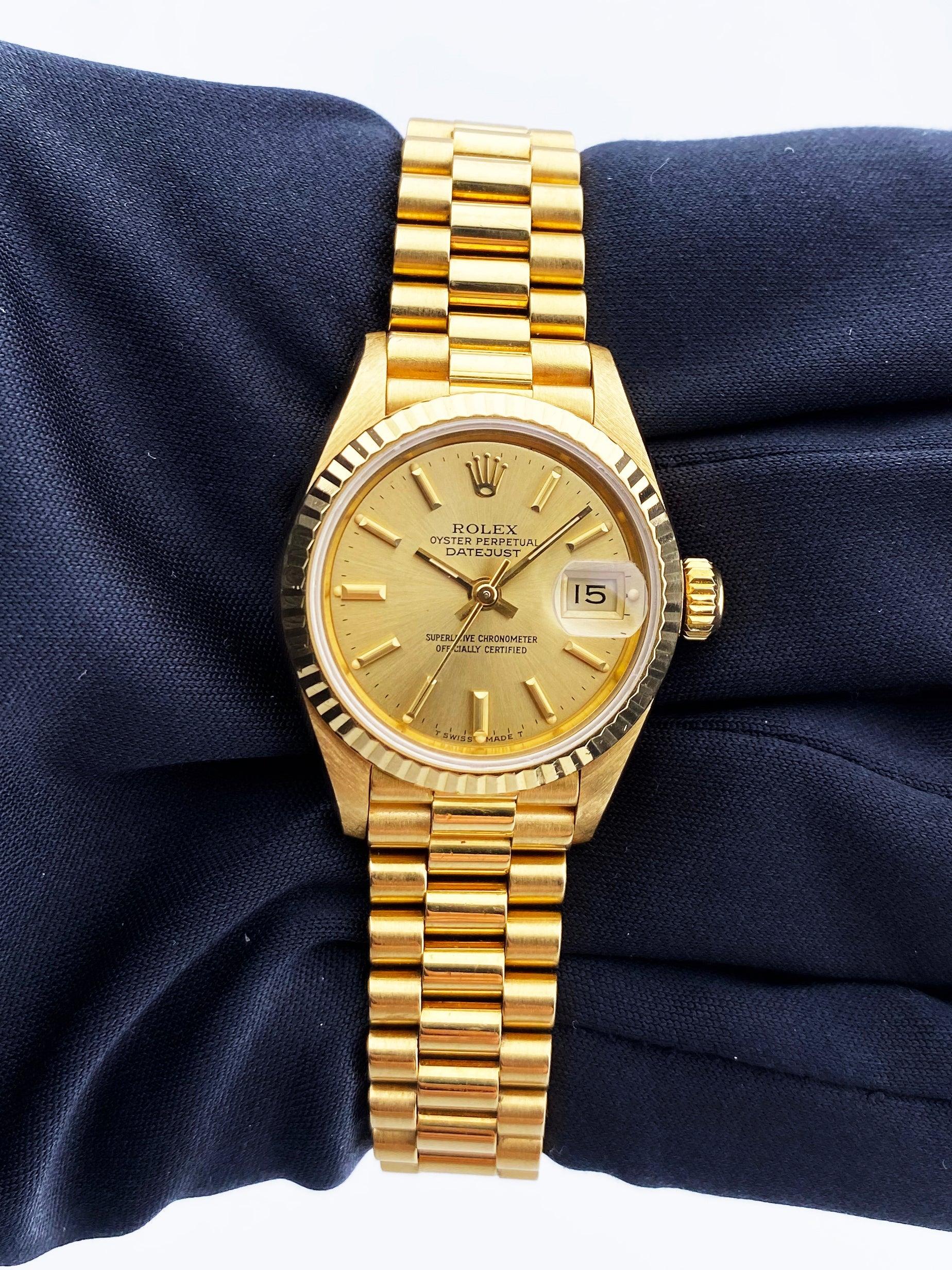 
Rolex Oyster Perpetual Datejust 69178 Ladies Watch. 26mm 18K yellow gold case with a fluted bezel. Champagne dial with gold hands and index hour markers. Minute markers on the outer dial. Date display at the 3 o'clock position. 18K yellow gold