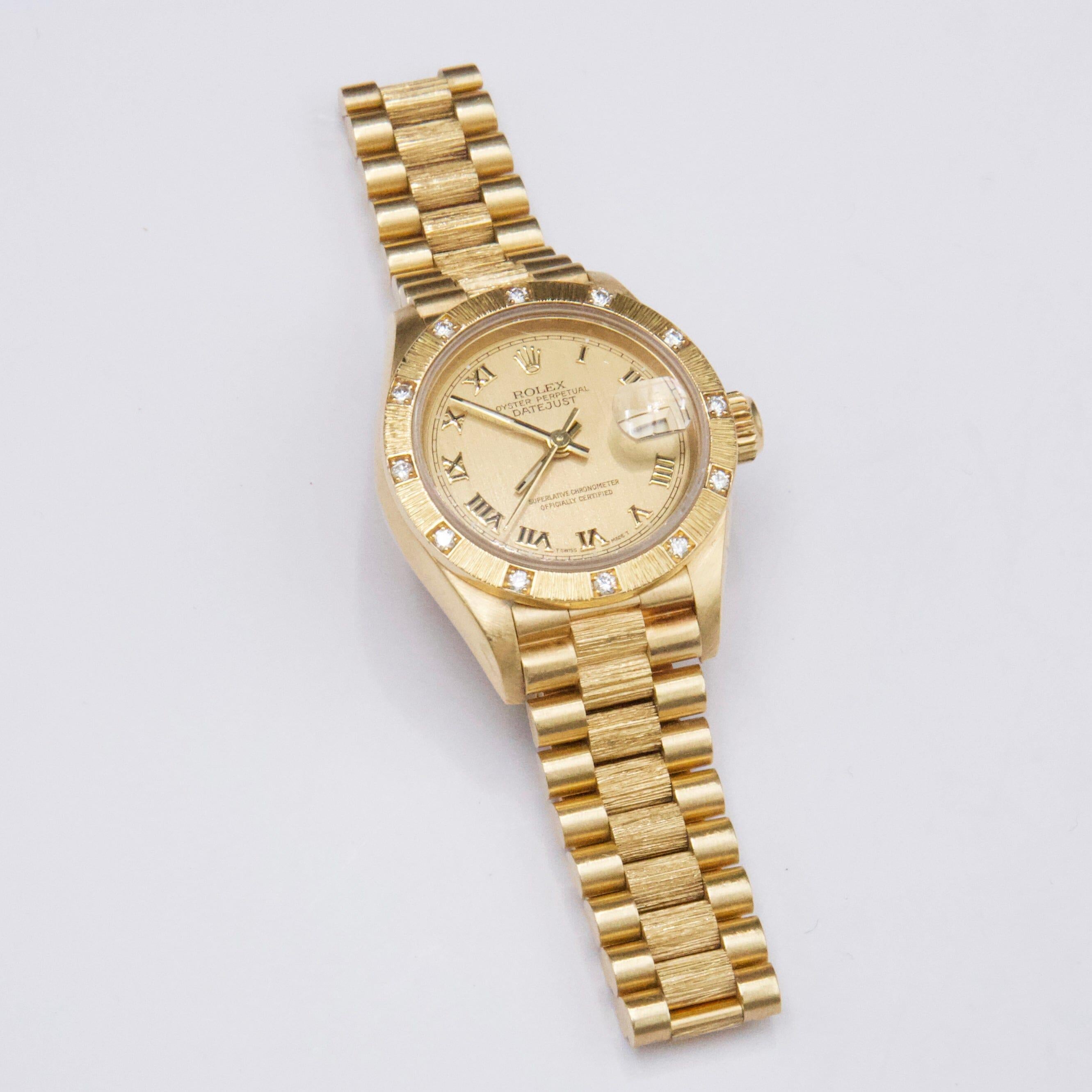 Rolex Datejust 69288 Ladies Watch. 26mm 18k Yellow Gold case. 18K yellow gold stationary bark bezel with factory diamond set. Champagne dial with gold hands and gold Roman numeral hour marker. The date is displayed at the 3 o'clock position. 18K