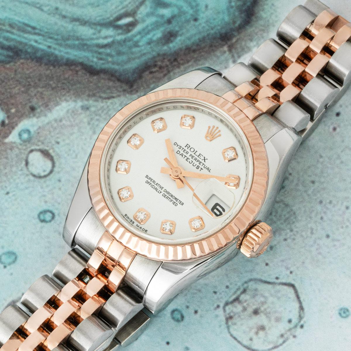 A 26mm Datejust in stainless steel and rose gold by Rolex. Features a white dial with 10 diamond set hour markers and a fluted rose gold bezel. Presented on a Jubilee bracelet which is equipped with a concealed folding Crownclasp. The watch is also