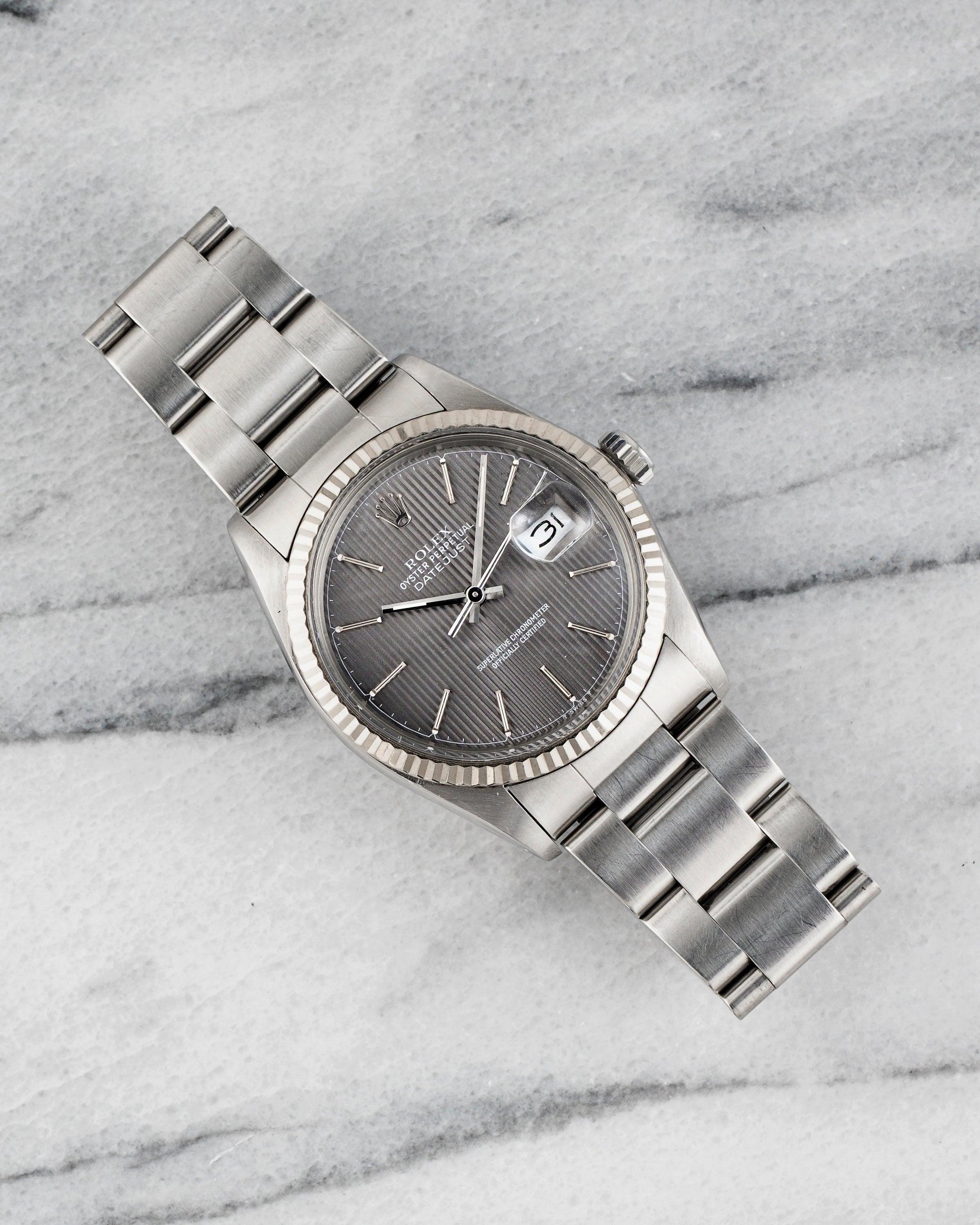 Ecco un Rolex Datejust d'epoca referenza 16014 (lunetta in oro bianco) automatico con quadrante grigio arazzo su un pesante bracciale oyster degli anni '80. Tiene benissimo il tempo ed è perfettamente funzionante. Le misure includono una cassa