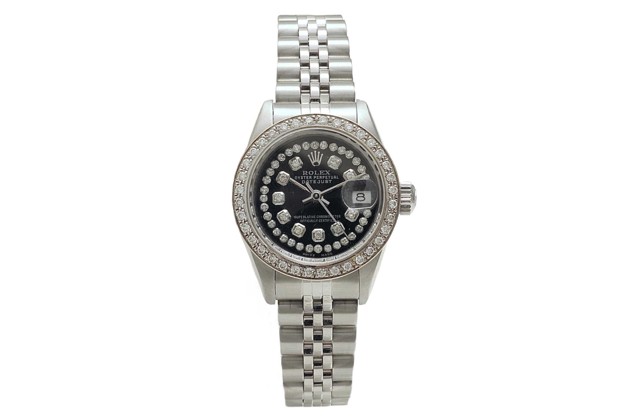 Rolex Datejust Oyster Perpetual Stainless Steel diamond set.

Movement: Automatic, Self winding

Functions: Hours, Minutes, Seconds, Magnified date window at 3 O'clock

Case: Stainless steel case, Diameter 26 mm, Diamond set bezel aftermarket

Dial: