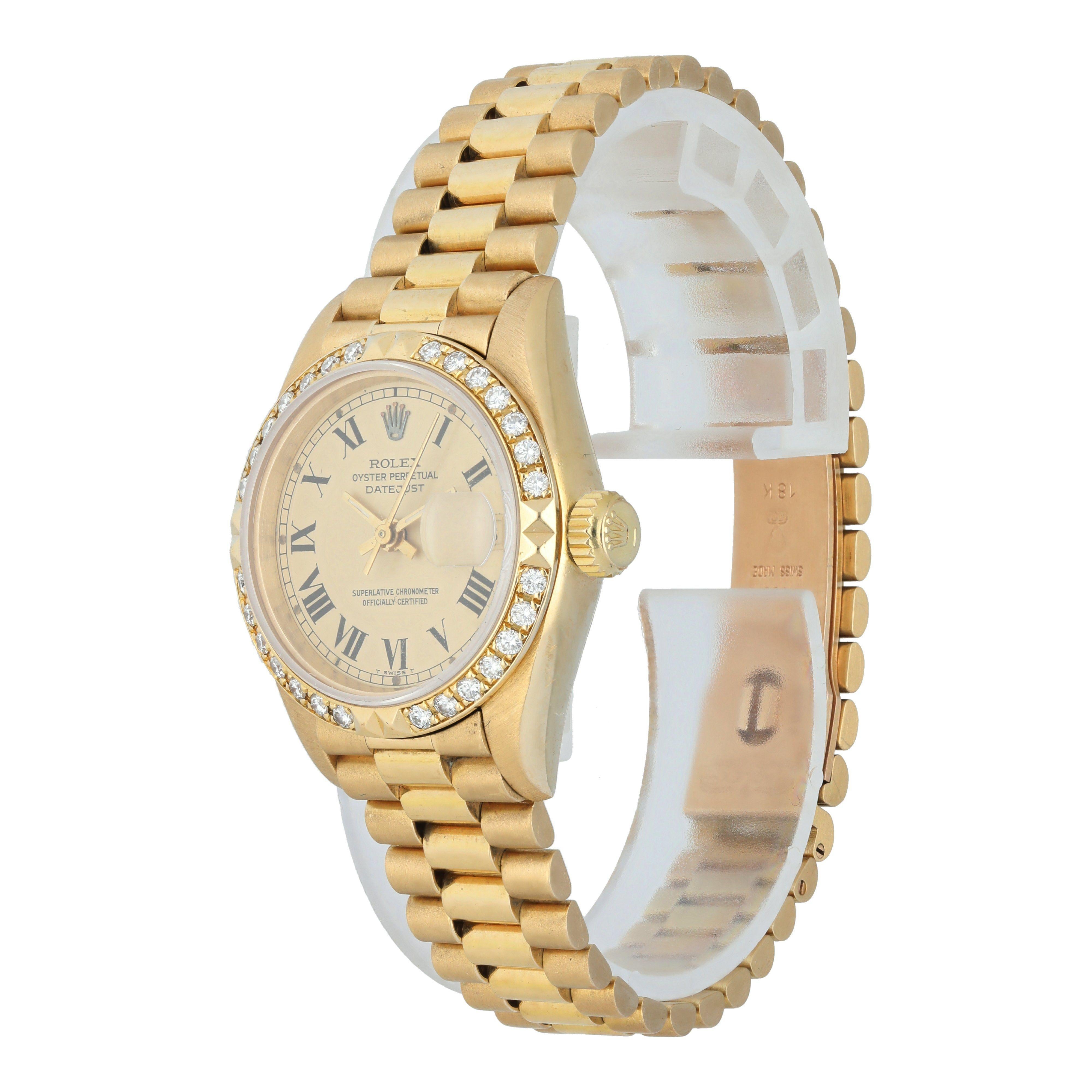 Rolex Datejust 69268 Ladies Watch. 
26mm Yellow-gold case. 
Factory diamond bezel.
Champagne dial with gold hands and roman numeral hour markers. 
Minute markers on the outer dial. 
Date display at the 3 o'clock position. 
Yellow Gold Bracelet with