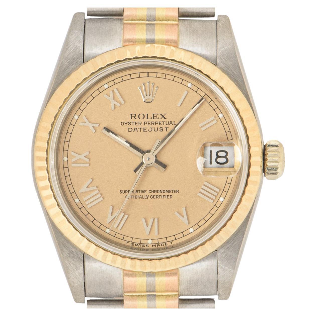 A captivating Datejust crafted in tri-gold by Rolex. Featuring a distinctive rose colored dial with applied roman numerals and a fixed yellow gold fluted bezel. Fitted with a sapphire glass, a self-winding automatic movement and an 18k tri-gold
