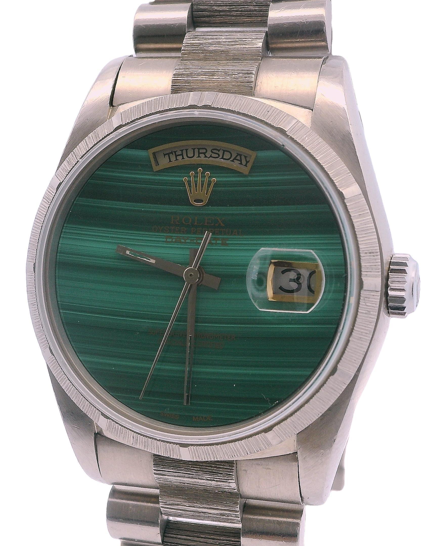 Rolex Day-Date Men's Watch 18249. This watch features a 36mm case made of 18K white gold and a bezel with a unique 18K white gold bark finish. The custom green malachite dial is complemented by gold hands. It includes a date display at the 3 o'clock