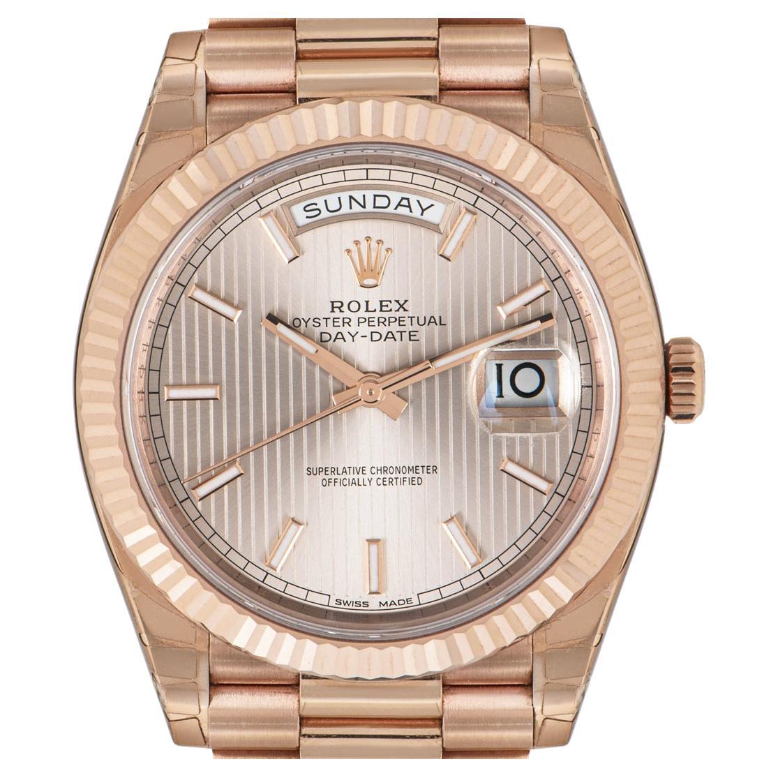 A stunning unworn Day-Date, crafted in 18k rose gold by Rolex. Featuring a sun dust stripe motif dial with applied hour markers. Complementing the dial is a fixed rose gold fluted bezel, unique to the Rolex design.

Equipped with a president