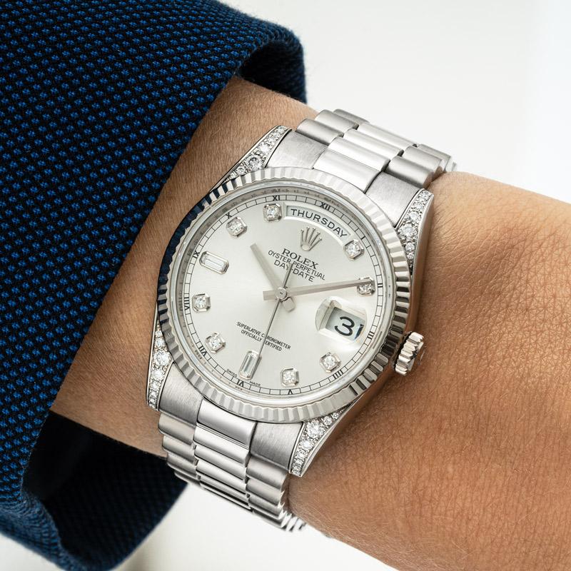 A 36mm white gold Day-Date by Rolex. Featuring a silver dial with diamond set hour markers and fluted white gold bezel as well as lugs set with 32 round brilliant cut diamonds. Fitted with a sapphire glass, a self-winding automatic movement and a